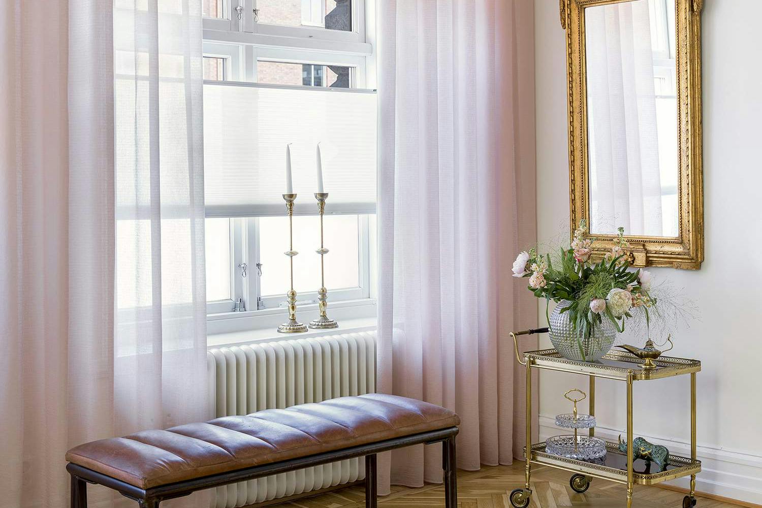 Translucent pink curtains layered with light pink duette shades in a living room