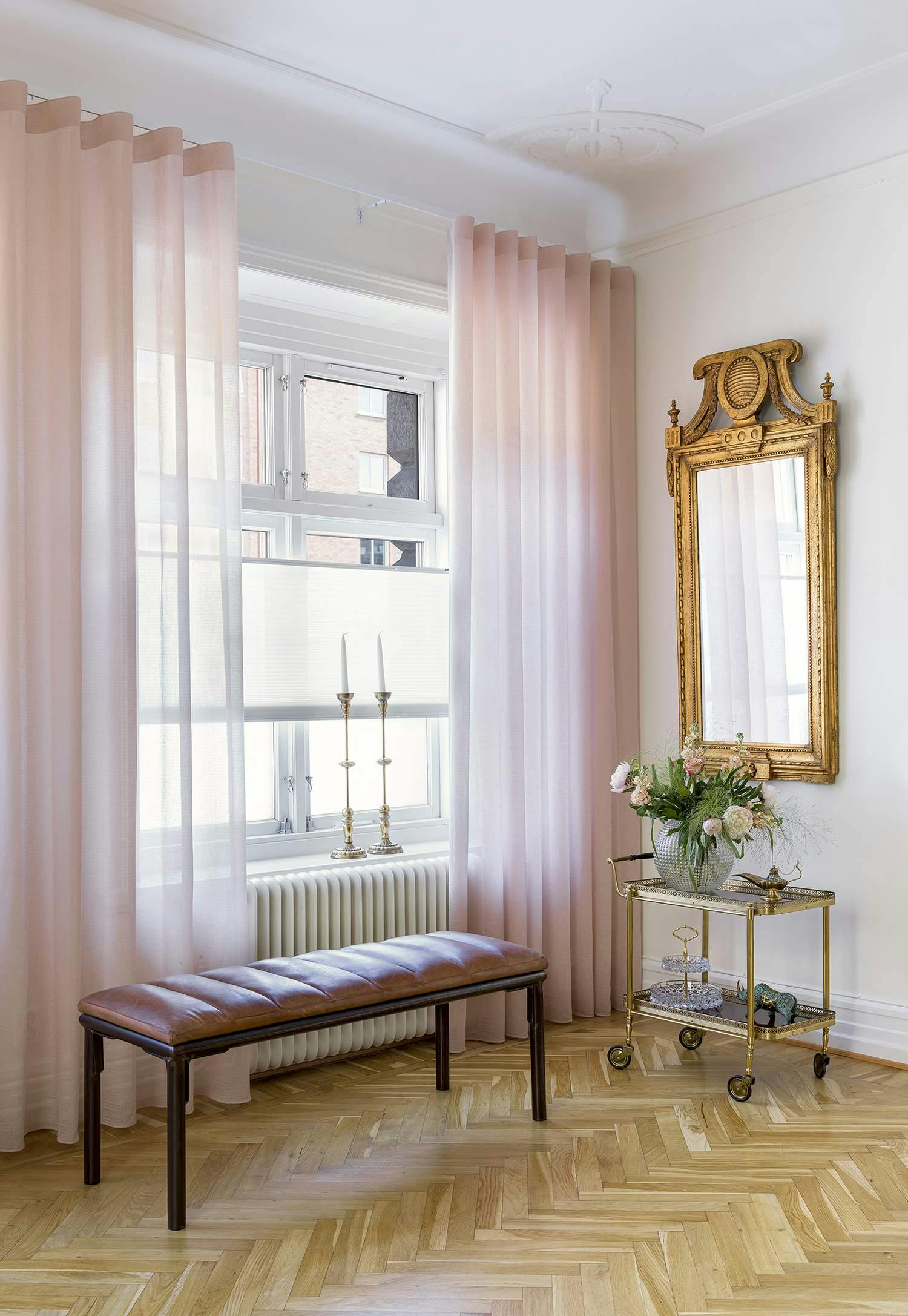 Translucent pink curtains layered with light pink duette shades in a living room