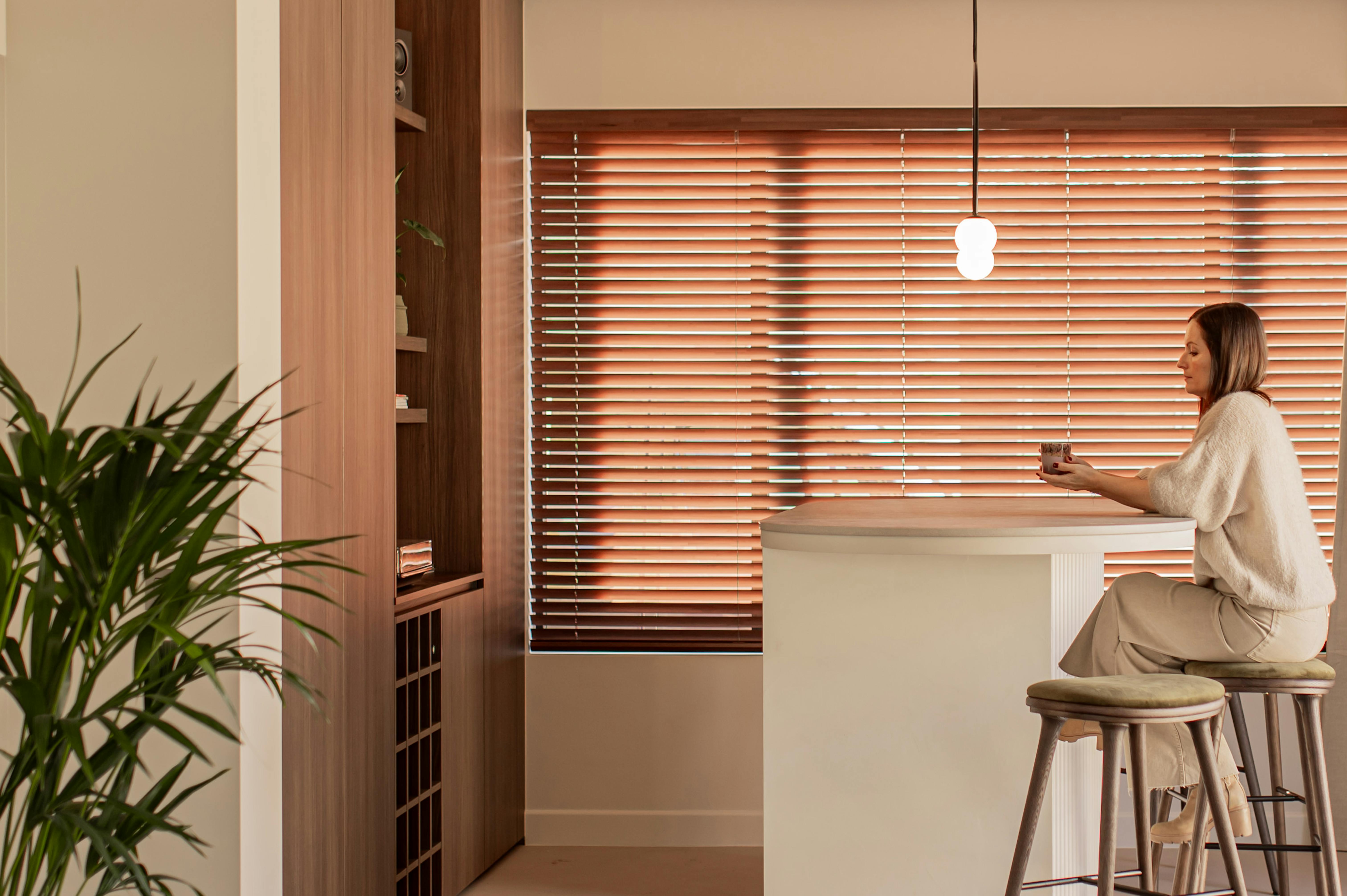 Stores en bois superposés à des rideaux crème dans une salle à manger