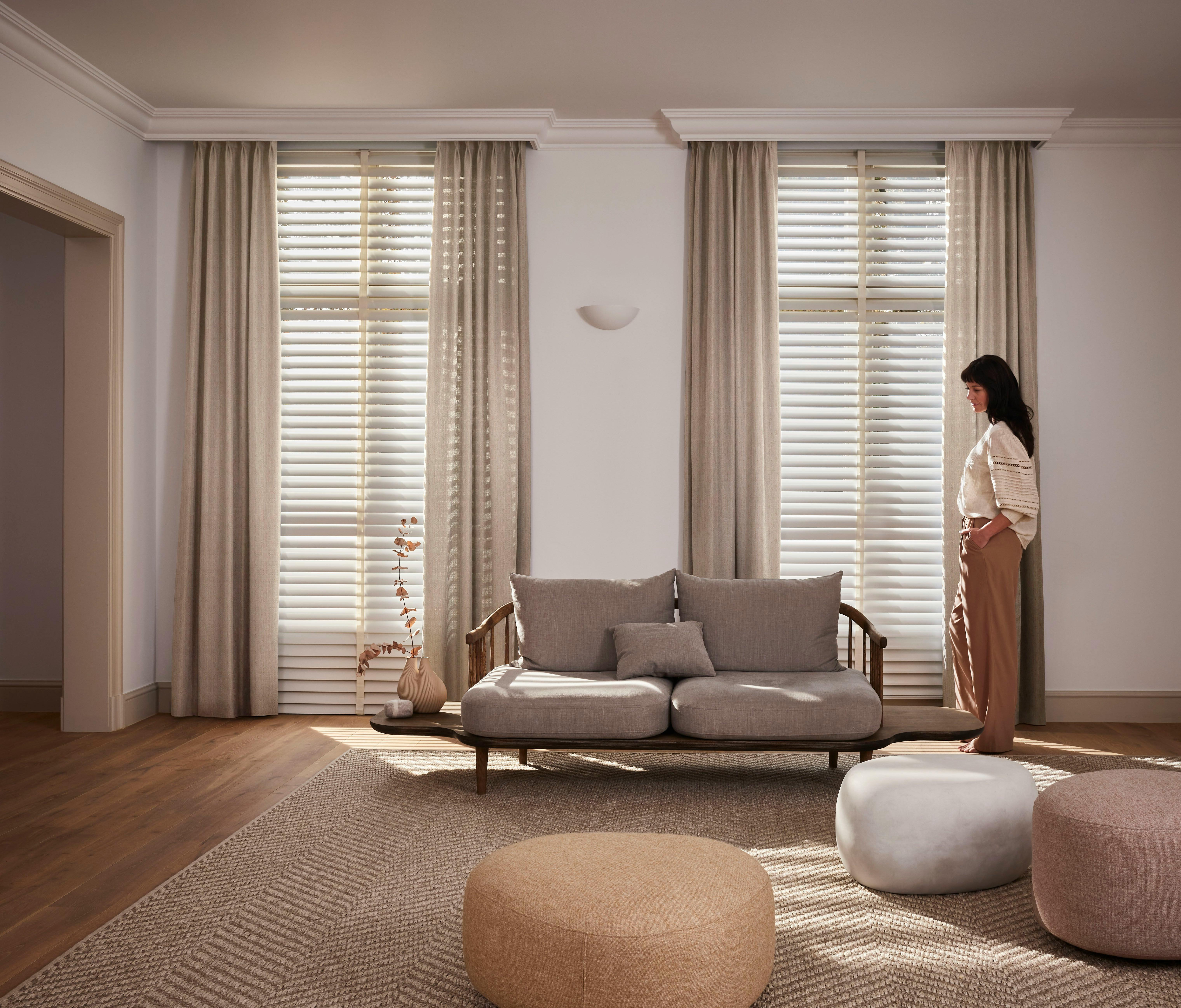 White venetian blinds layered with cream curtains in a living room