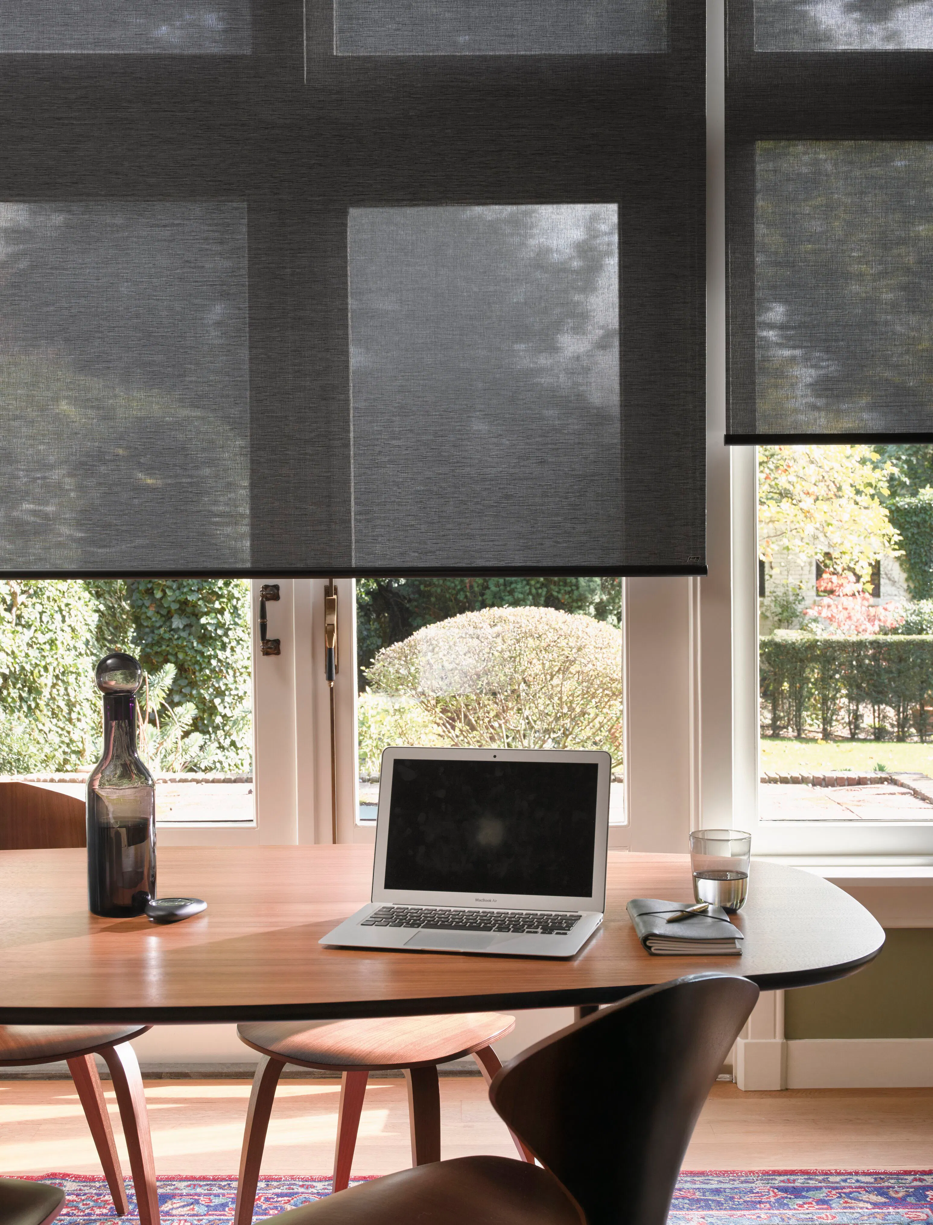 Two black roller blinds on full height windows in an office