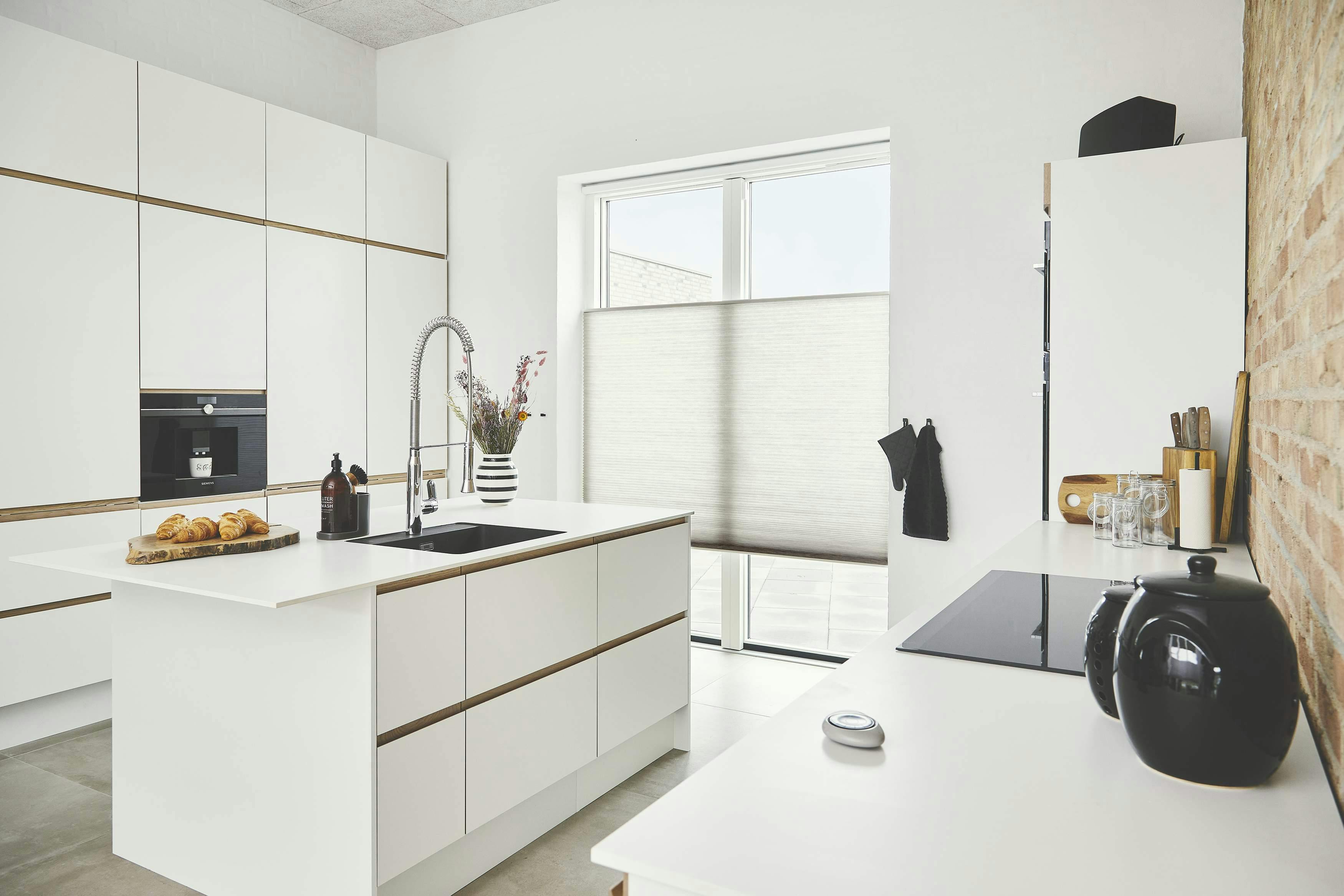 Bright white modern kitchen with white duette blinds covering patio doors