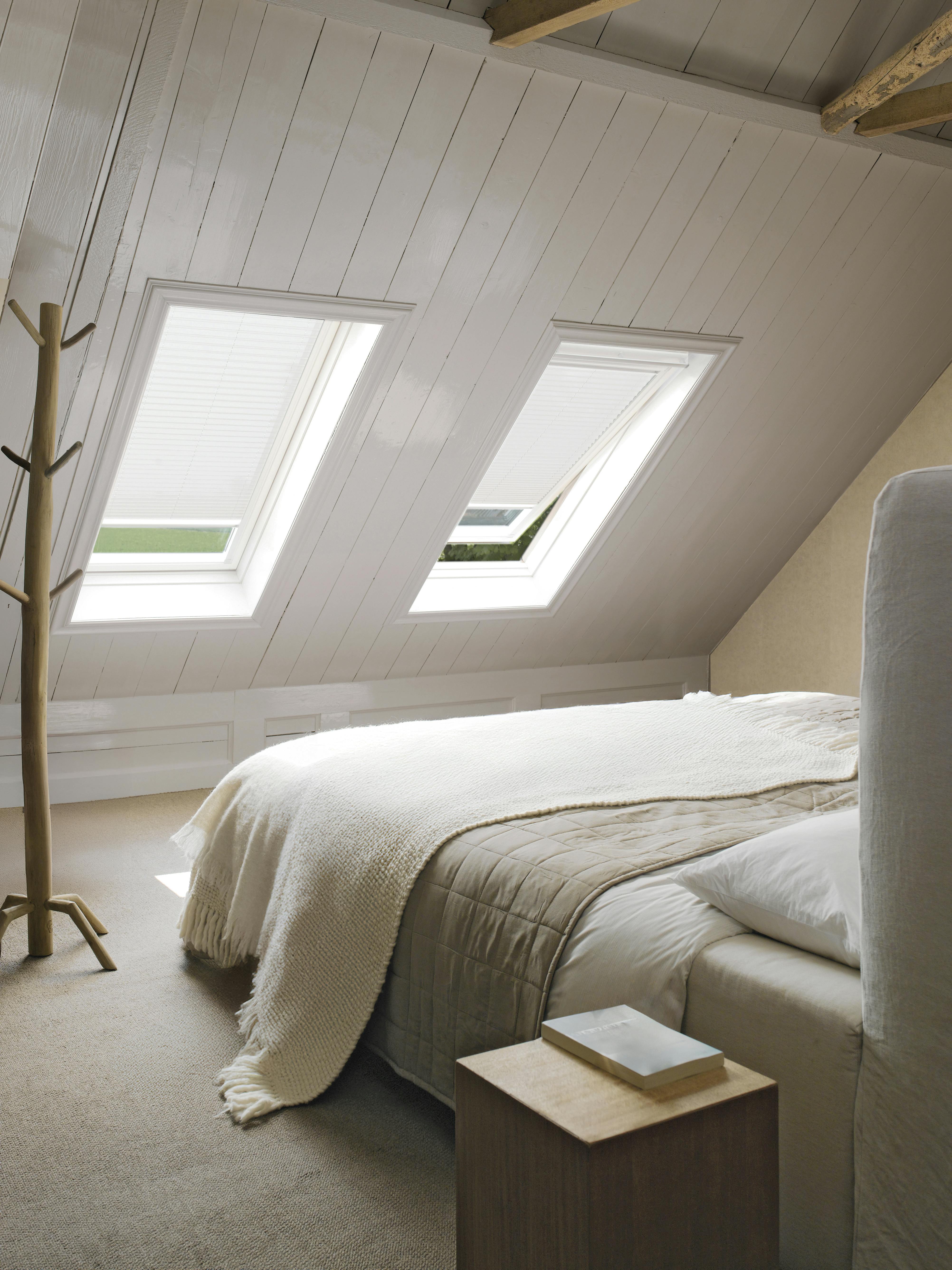 Hvide plisségardiner i et ovenlysvindue i et soveværelse