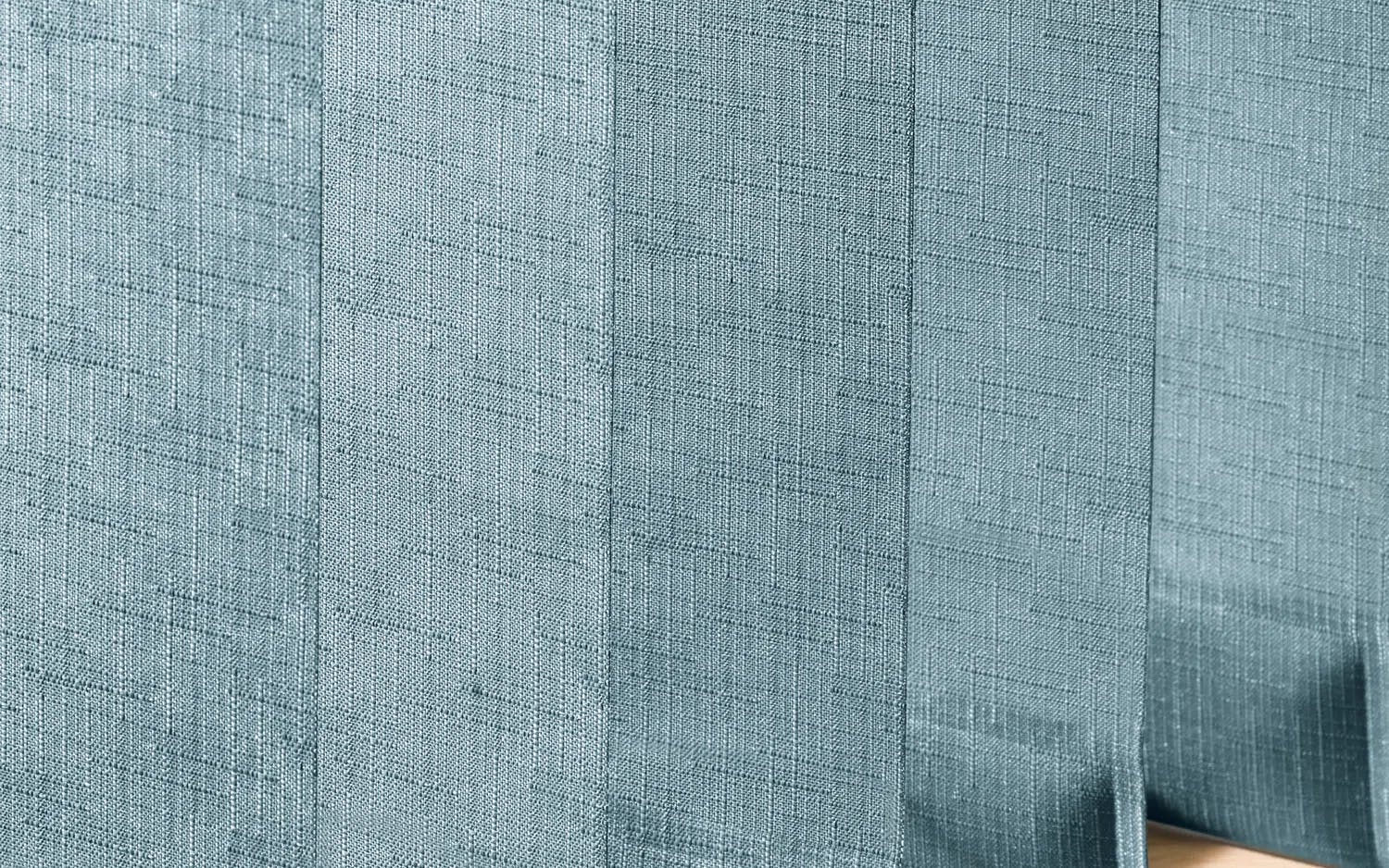 Närbild på ett texturerat tyg i ljusblå eller teal färg med vertikala veck. Tyget har ett subtilt vävt mönster som framhävs av skuggor och ljus.