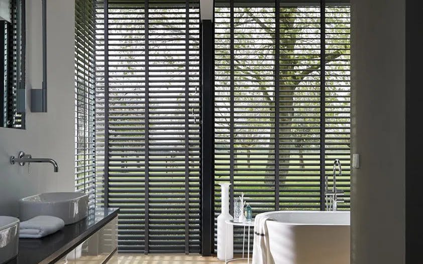 Black venetian blinds on big windows in a bathroom