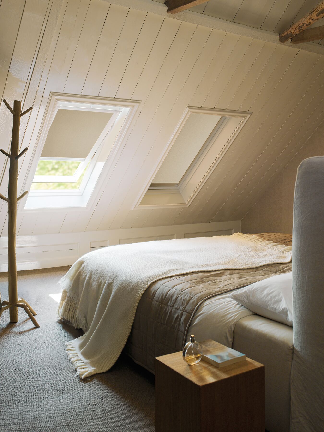 White roller blinds on a skylight window in a bedroom