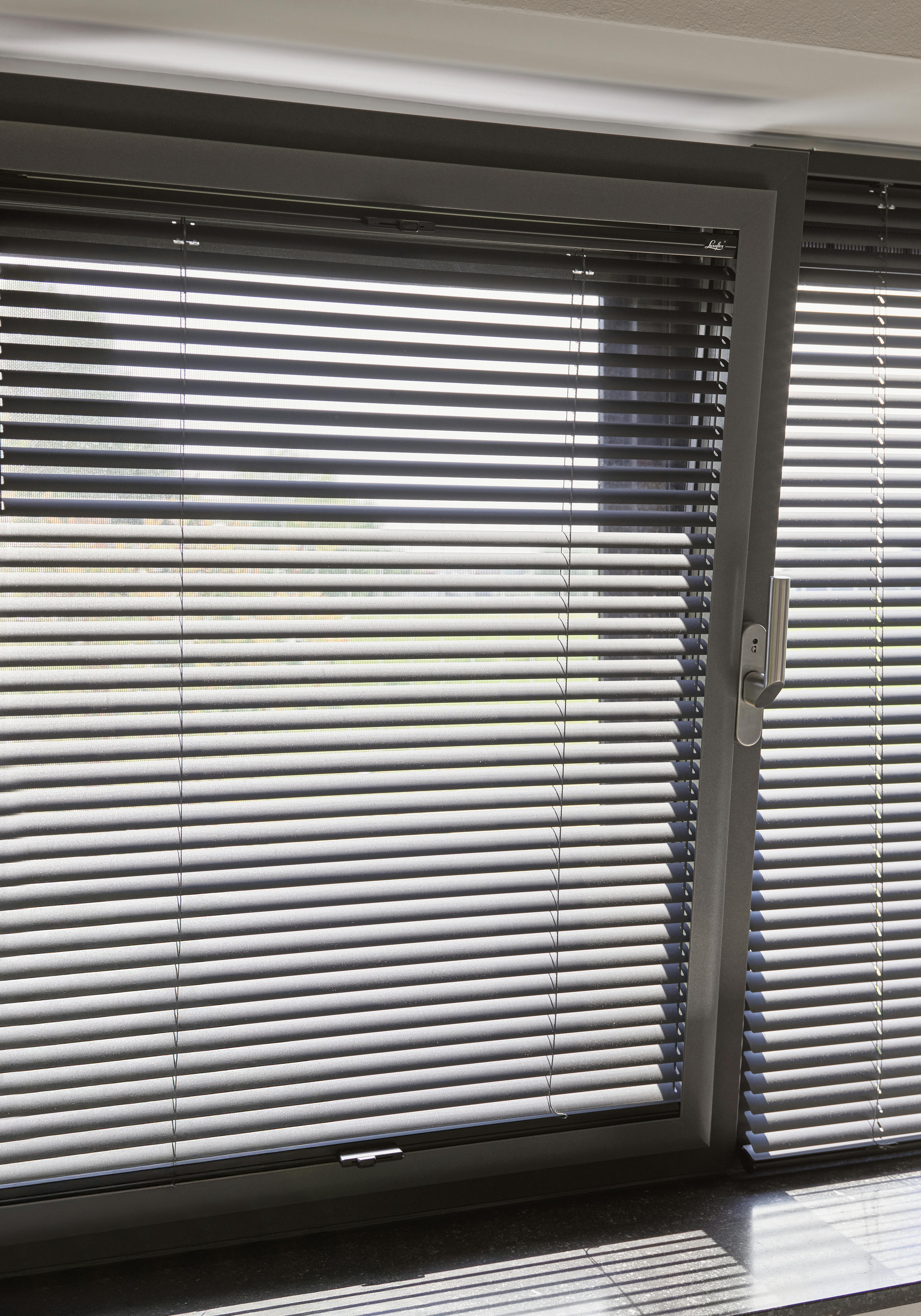 Närbild på svarta persienner i vippfönster