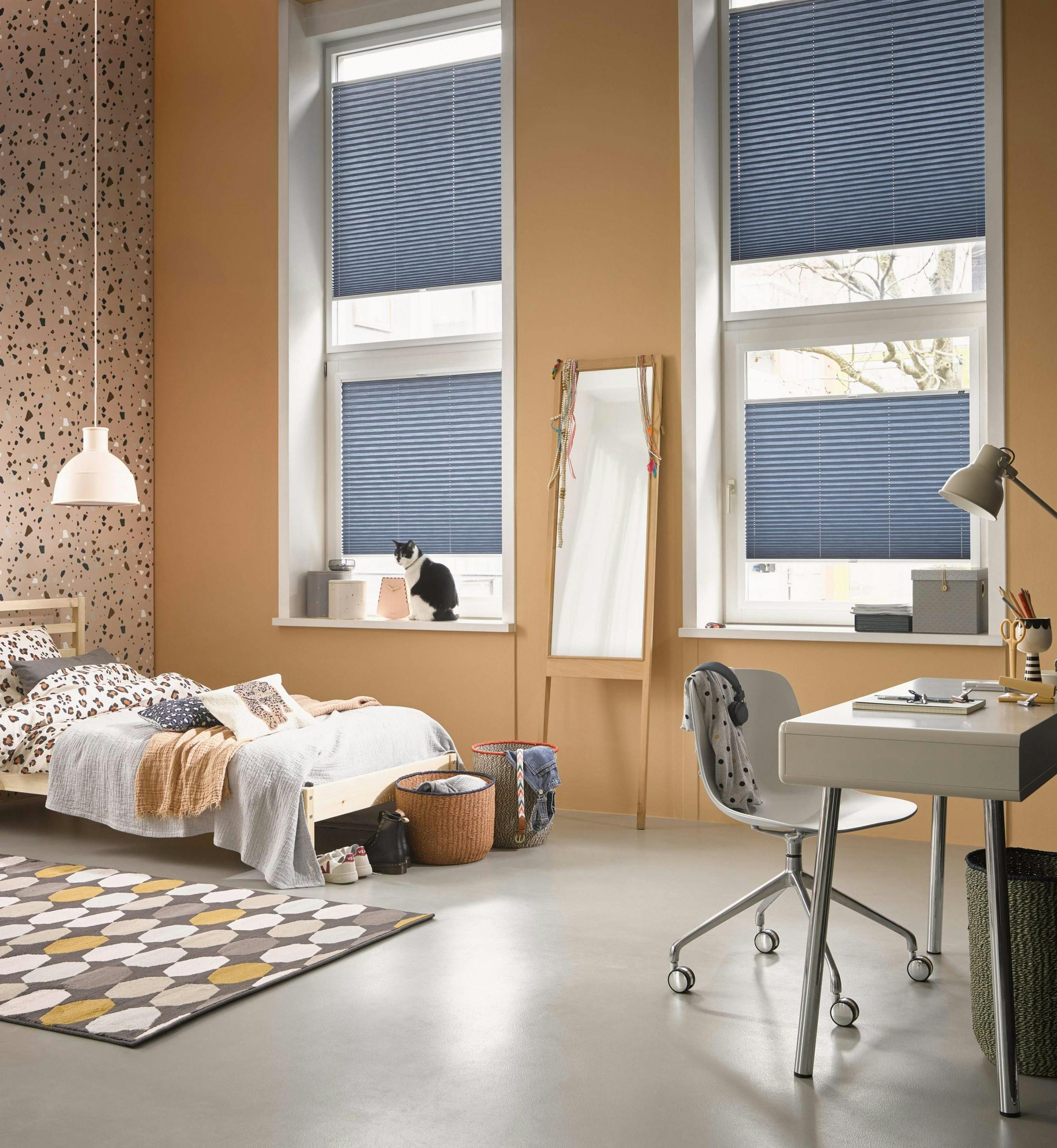 Spacious bedroom with blue plissé shades on windows