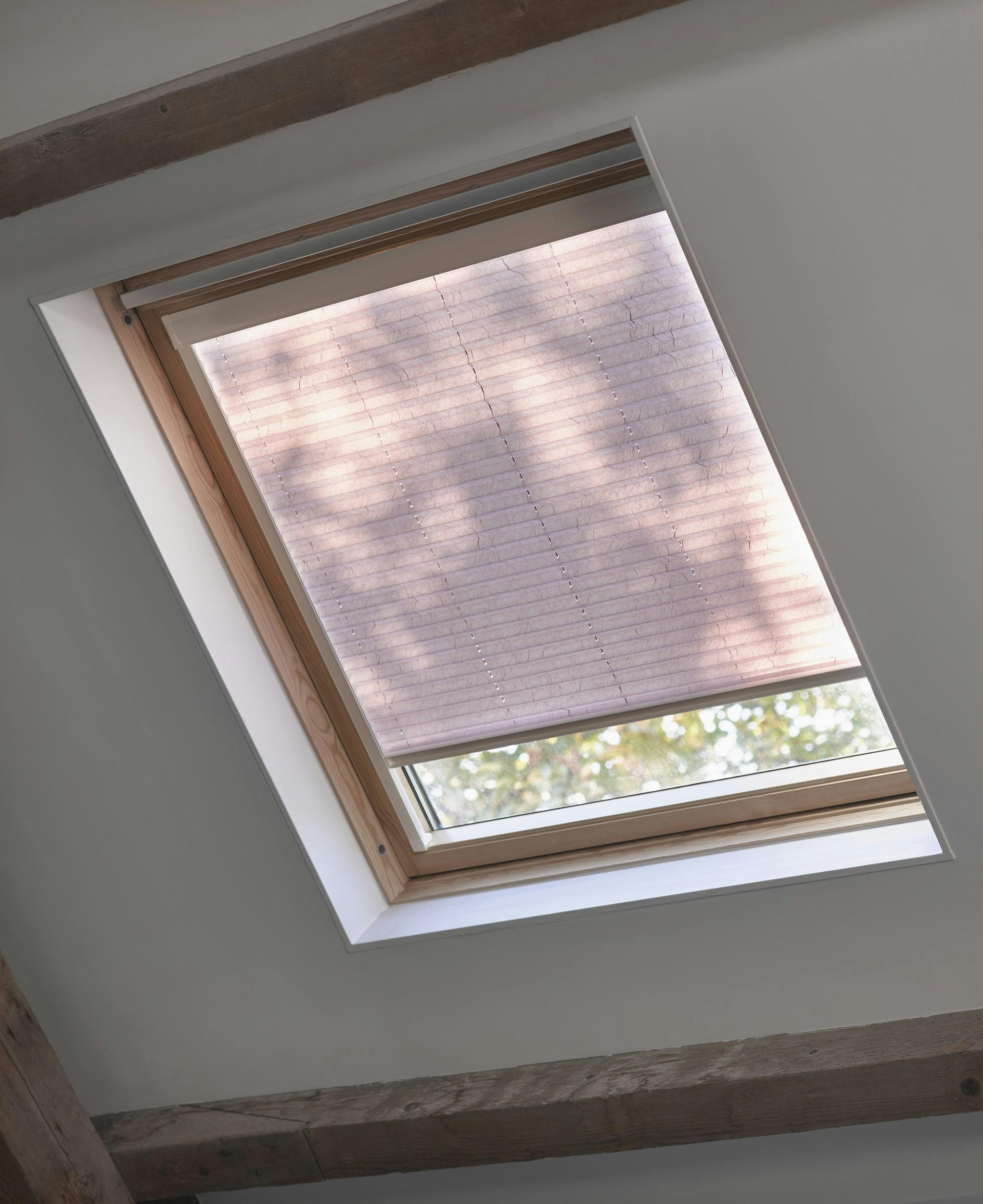 Roze plissé gordijnen op een dakraam