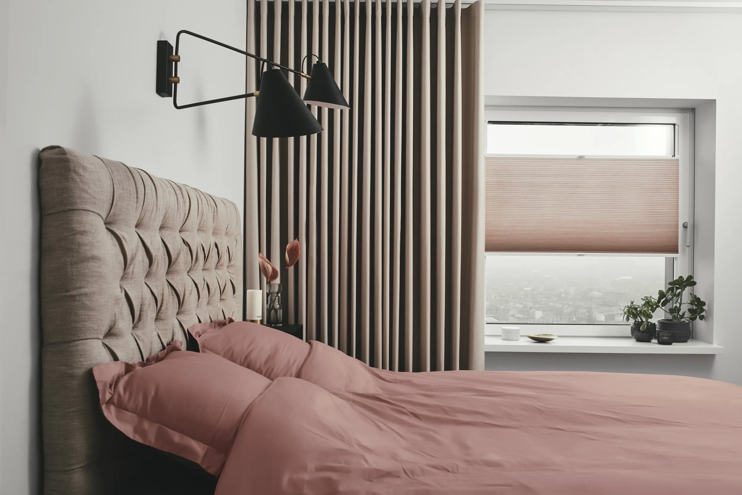 Pink duette shades layered with a pink curtain in a bedroom