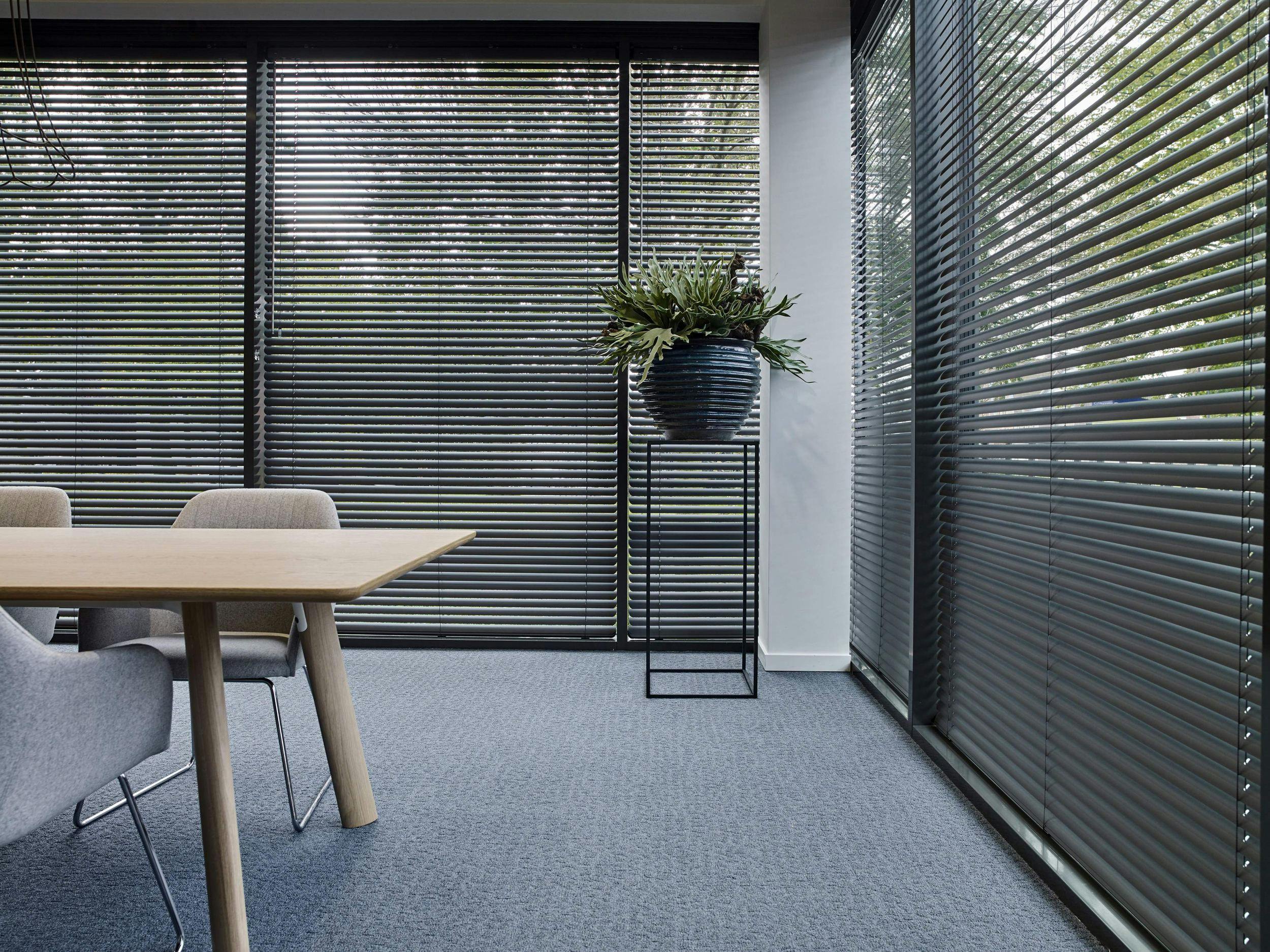 Spacious room with black venetian blinds on large windows