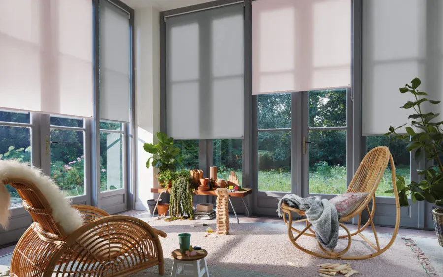 White and grey roller blinds on windows and patio door in a light-filled living room
