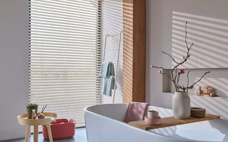 Light venetian blinds on large window in a modern bathroom
