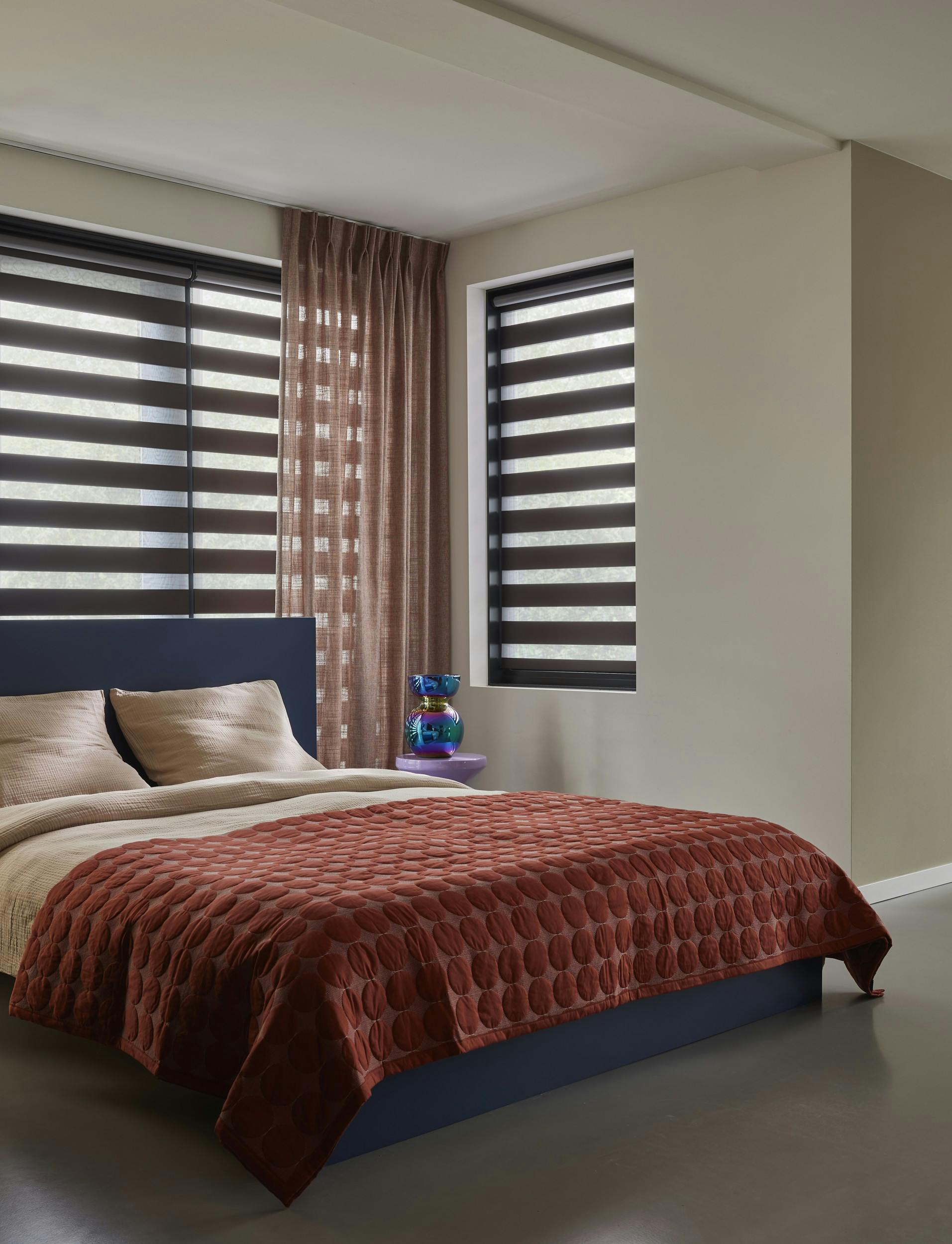 Bruine duo rolgordijnen op ramen in een moderne slaapkamer