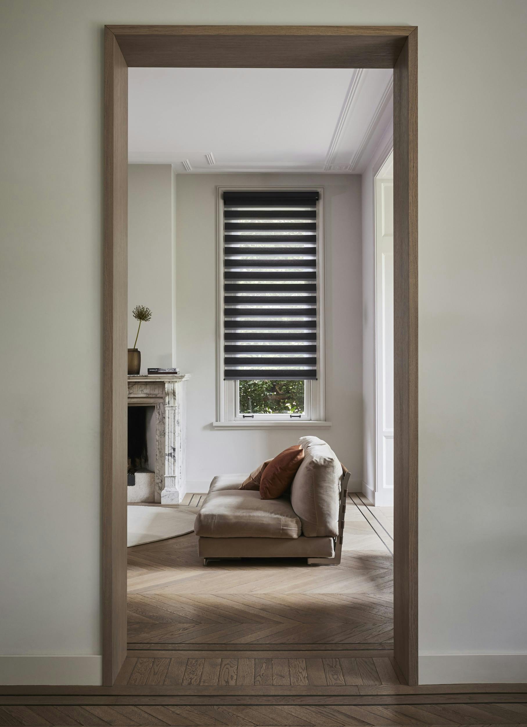 Stores enrouleurs duo bruns sur une fenêtre dans un salon vus de loin