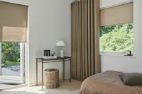 Moderne slaapkamer met beige rolgordijnen op een raam en een tuindeur