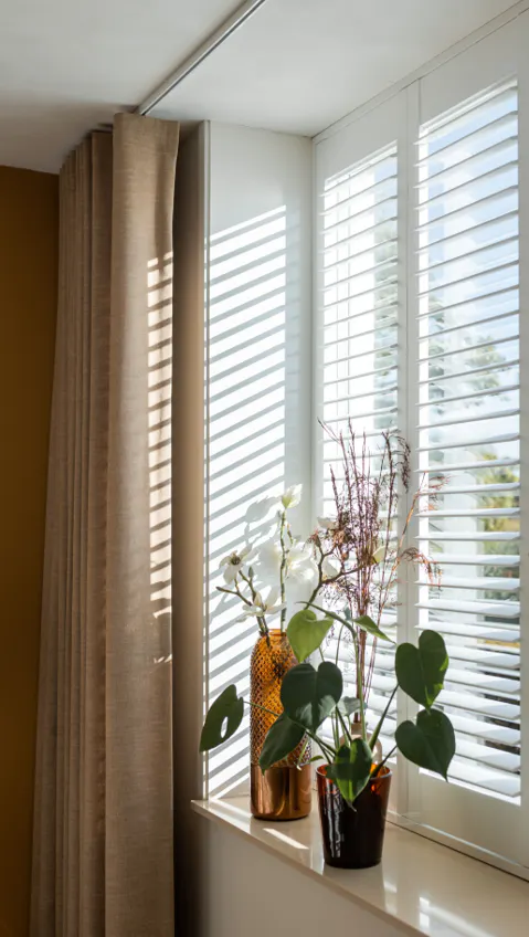 White shutters layered with beige curtains