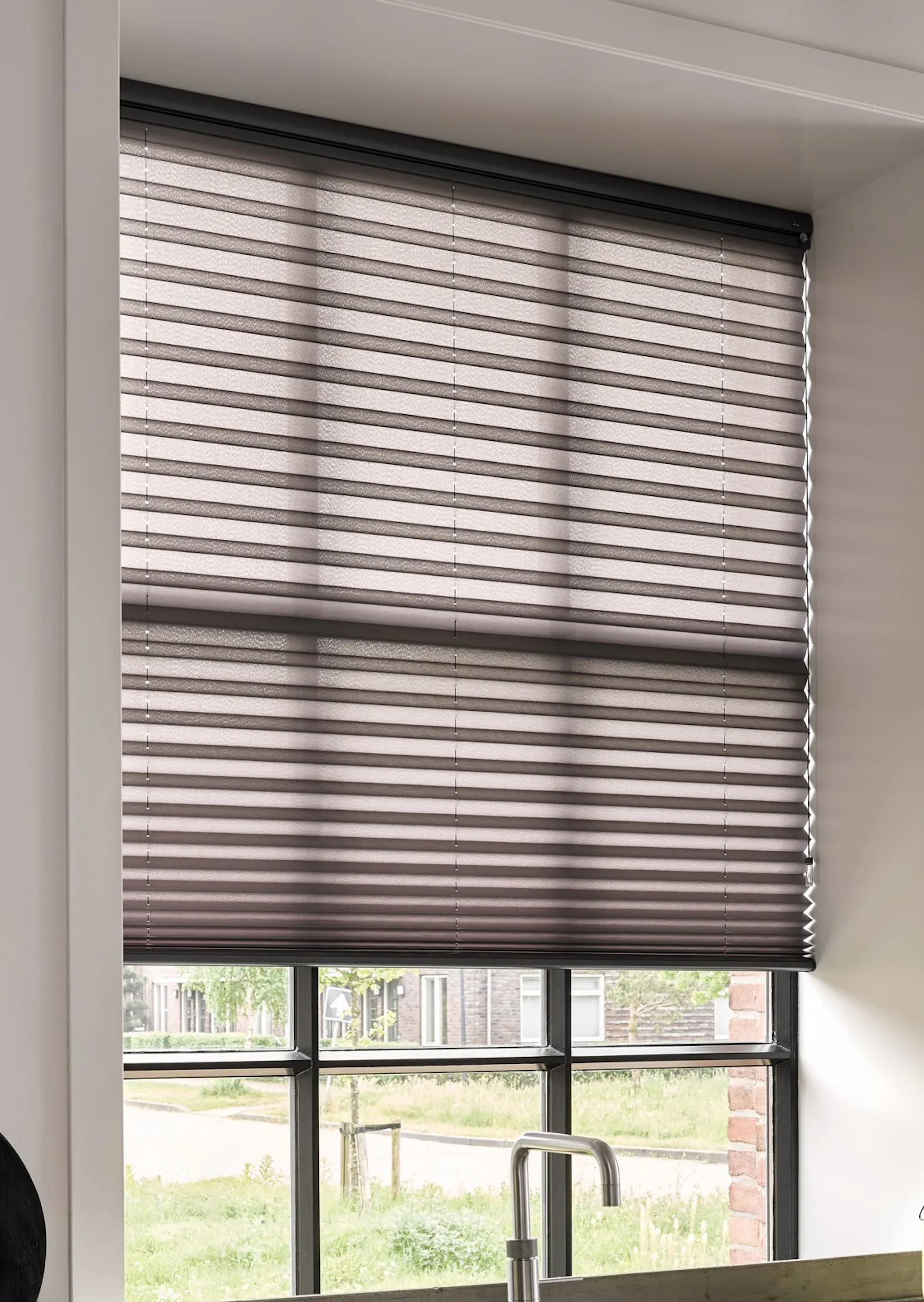 Sorte plisségardiner i et køkkenvindue