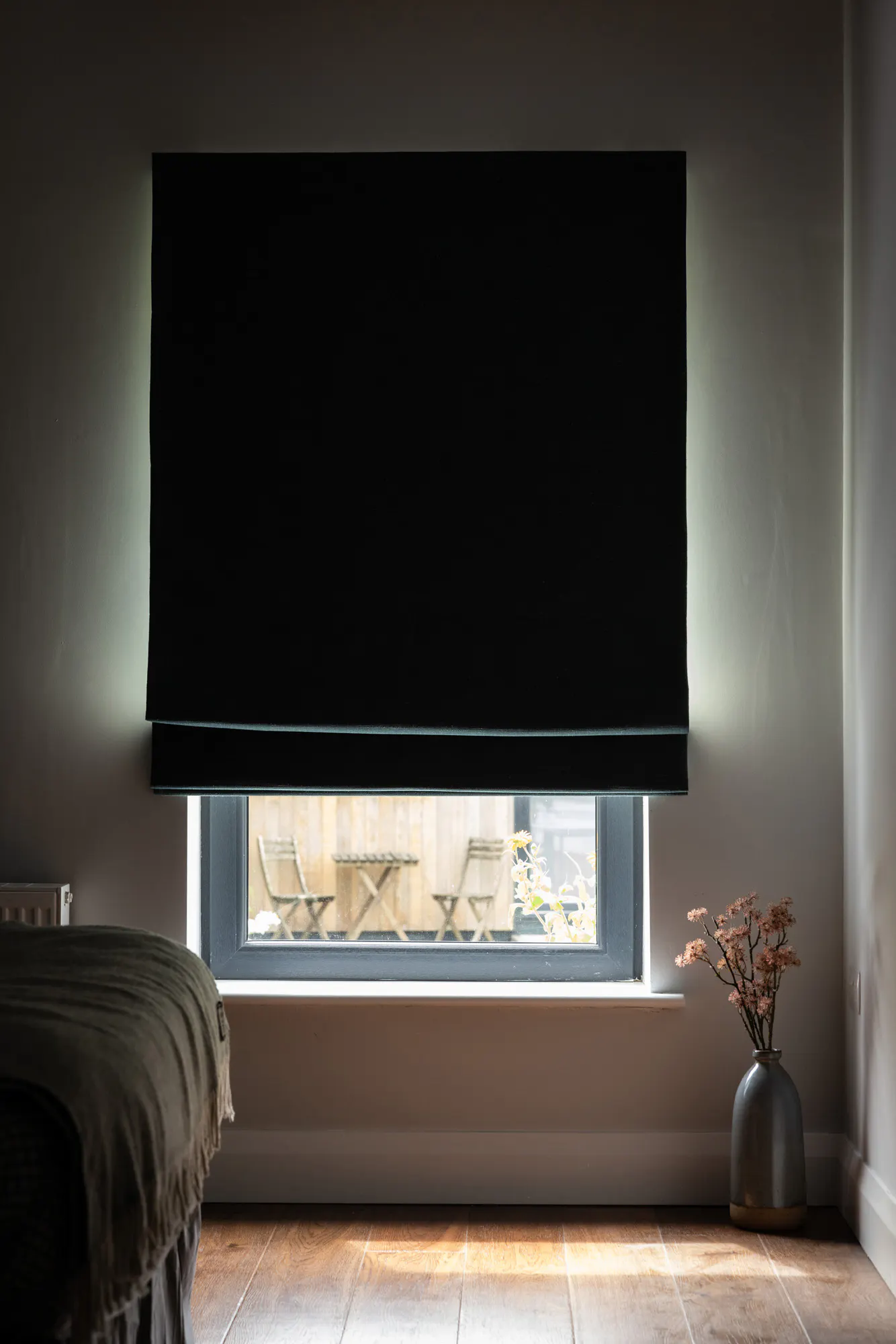 Dark green roman blinds in an semi-open position in a bedroom