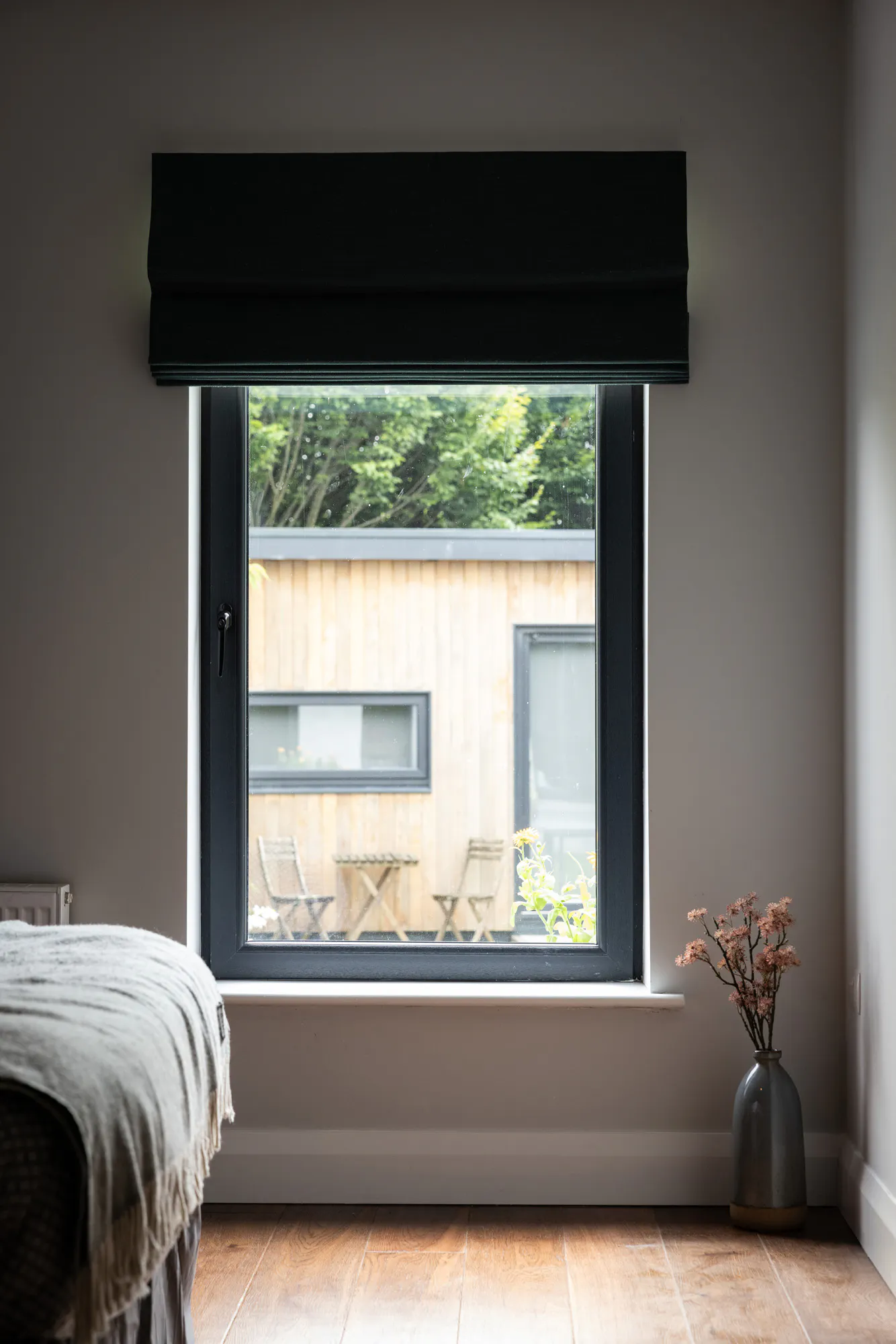 Dark green roman blinds in an open position in a bedroom