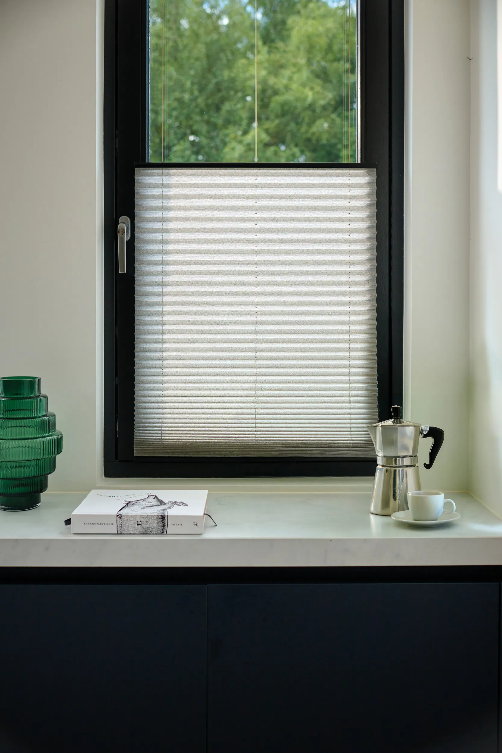 Witte plissé gordijnen op een raam in een moderne keuken