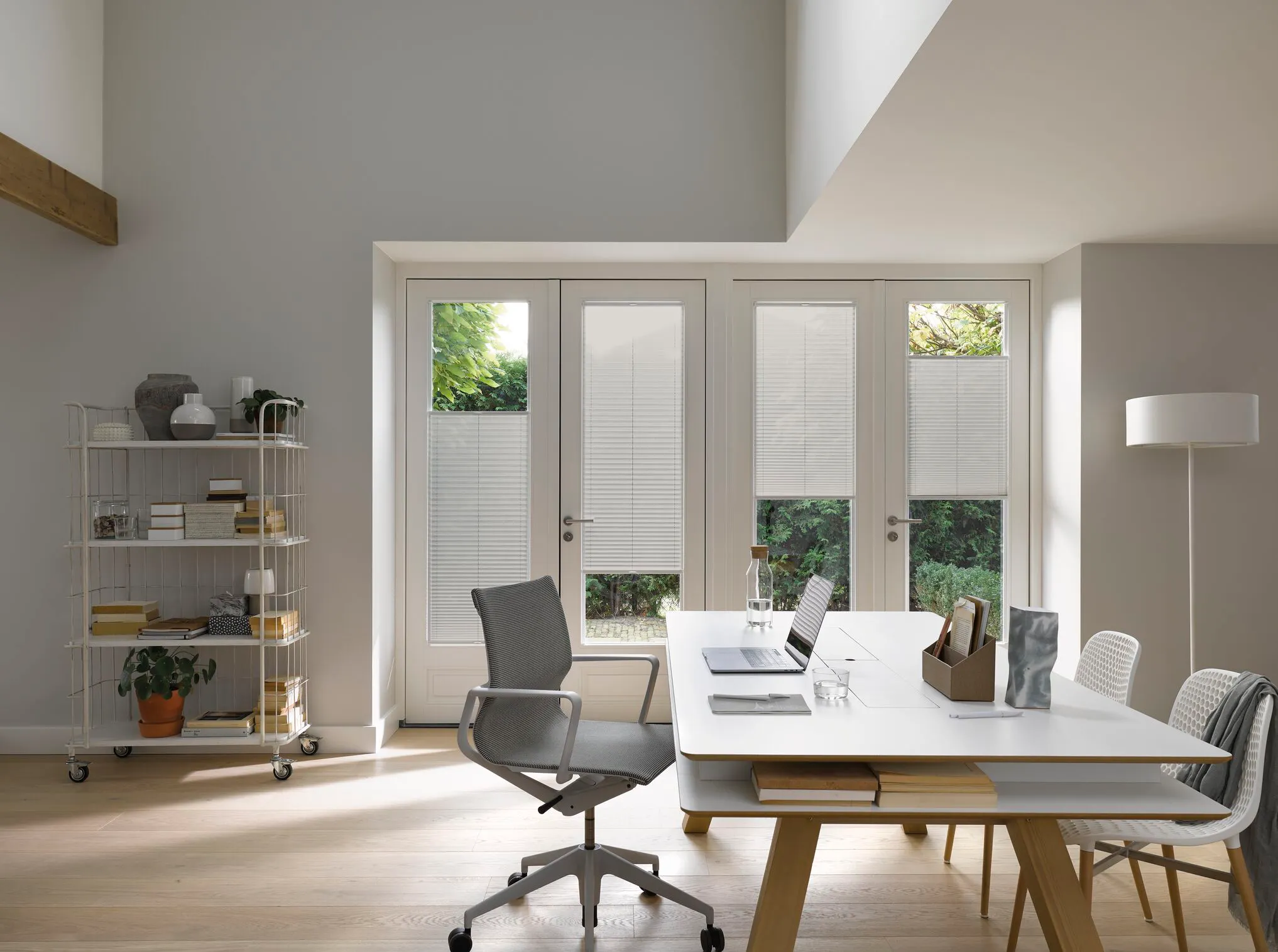 Großzügiges Homeoffice mit Giebel und einer großen Glasfront mit Türen und Fenstern, weiße Plissees mit Top-Down/Bottom-Up-Bedienung