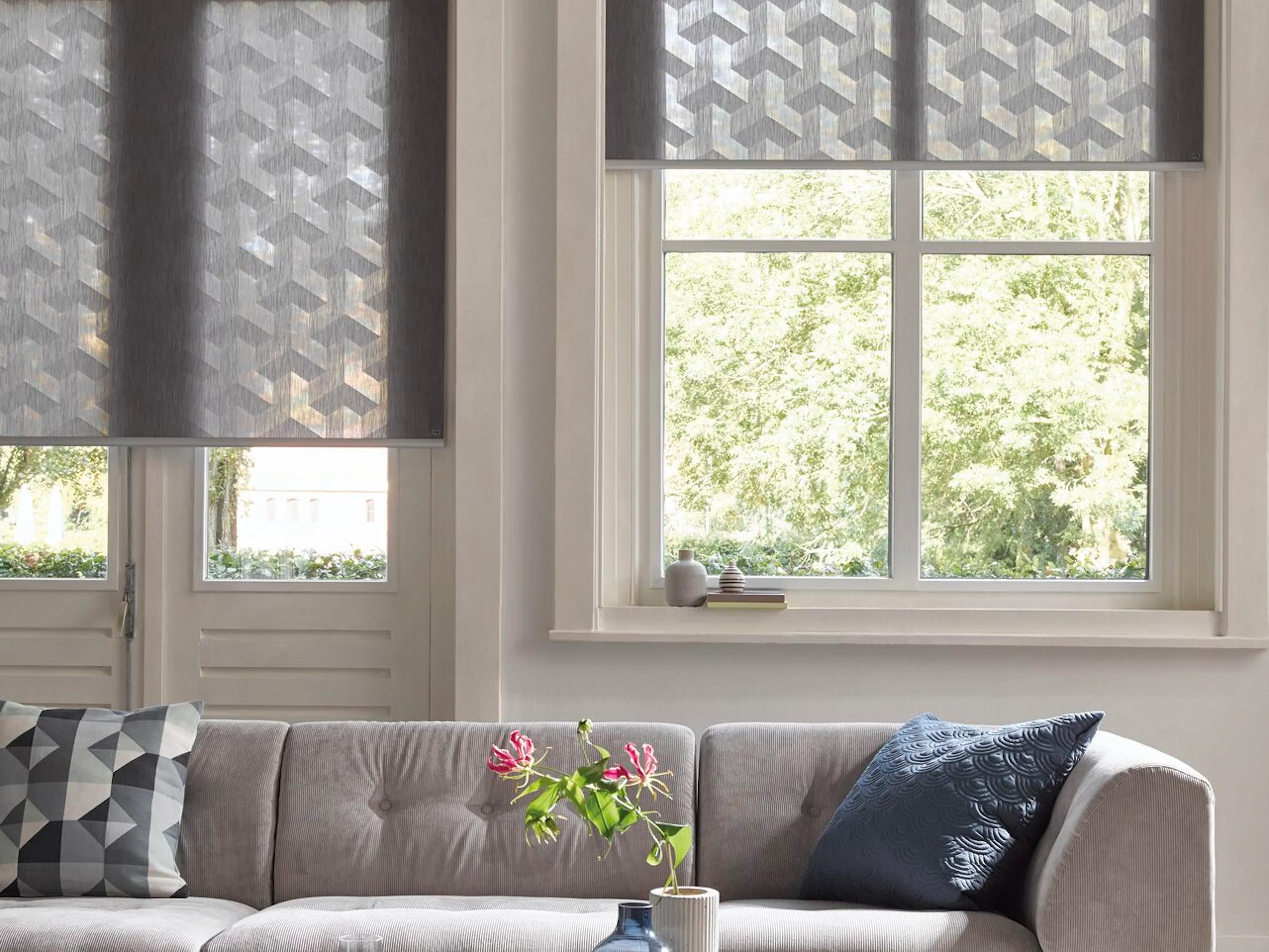 Blue roller blinds with white geometric designs in a living room