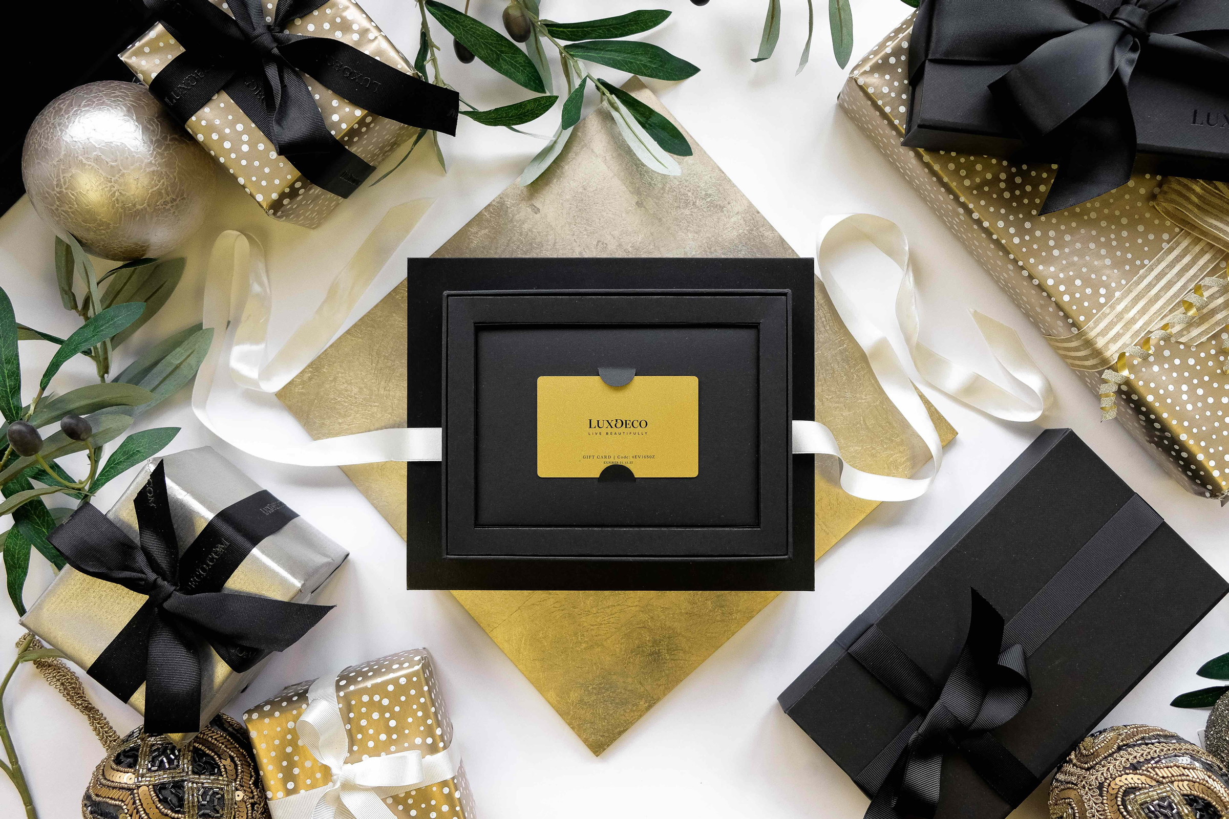 Golden LuxDeco gift card in presentation box next to beautifully wrapped Christmas gifts