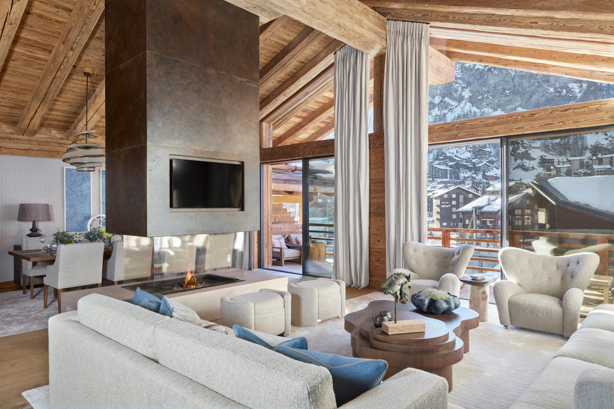 Katharine Pooley ski chalet living room with off-white upholstered sofas around an open fireplace