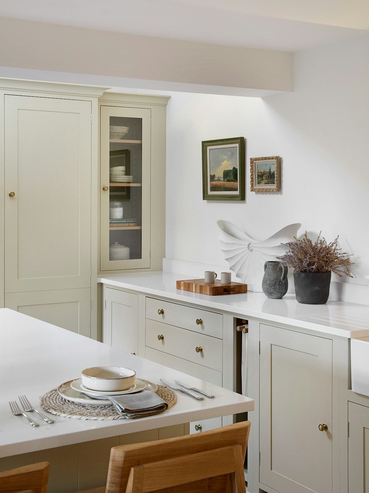 Calm white kitchen with bespoke cabinets and inviting place setting on the island 