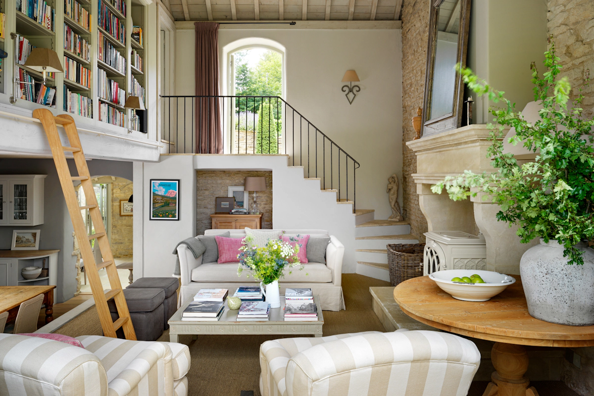 Emma Sims-Hilditch Wiltshire home living room with winding staircase, linen sofa and large stone fireplace