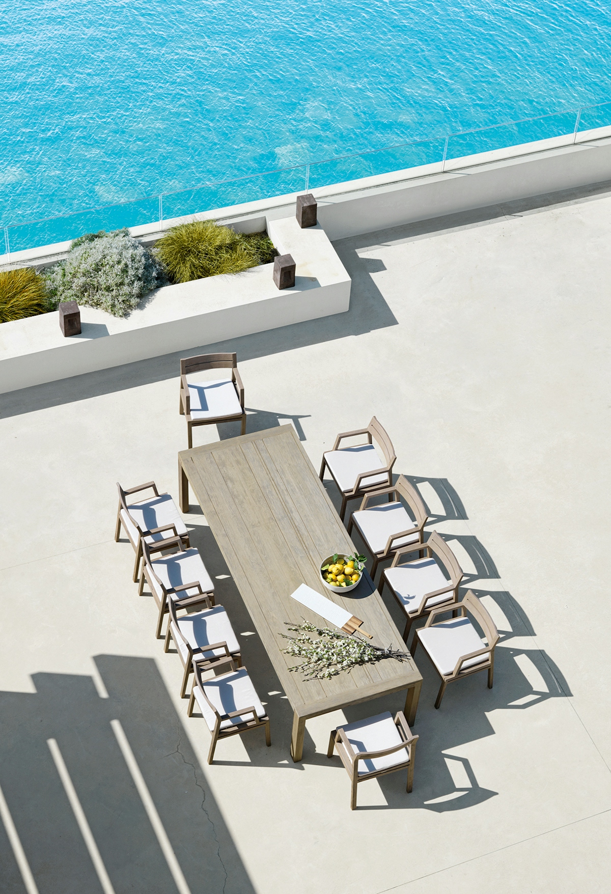 Ethimo Costes XL outdoor dining table and Costes teak outdoor chair against a seaside backdrop