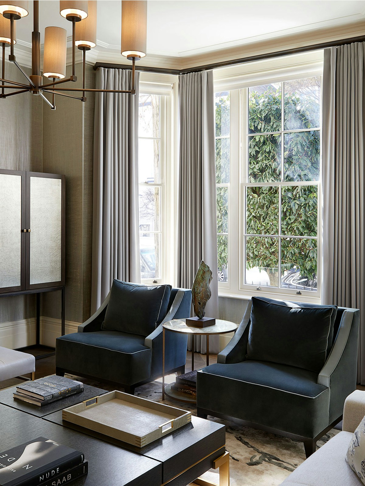 Blue velvent armachairs in bay window with dark wood coffee table with tray on top