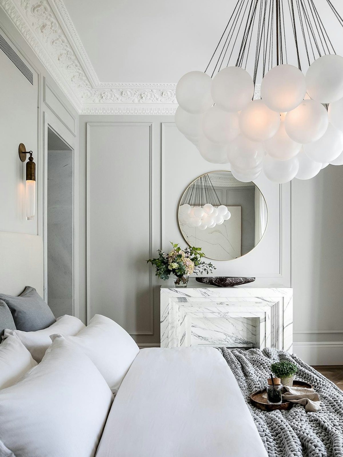 Elegant grey bedroom with modern white marble fireplace and bubble chandelier by Banda Property | The Quiet Luxury Lookbook