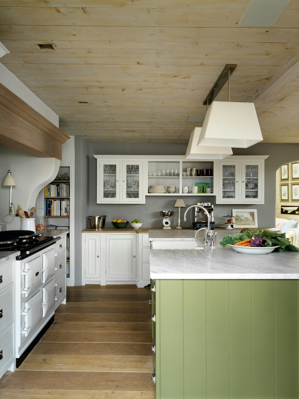 Emma Sims-Hilditch country kitchen with white and green cabinets and white marble worktop. Large AGA range and square pendant lighting