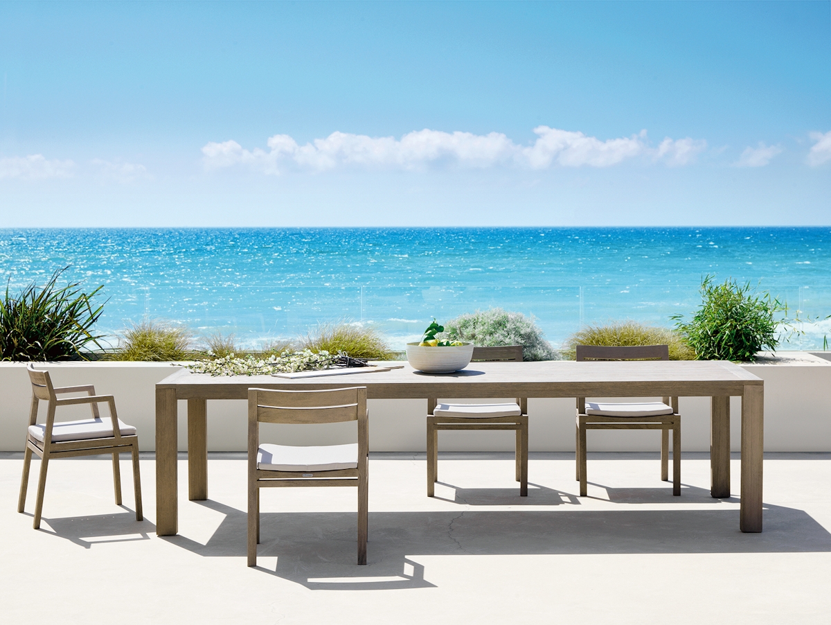 Ethimo Costes XL outdoor dining table and Costes teak outdoor chair against an expansive seaside backdrop
