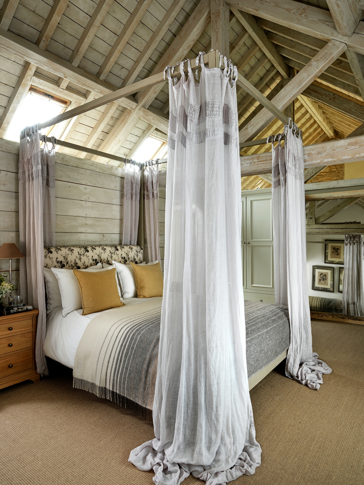 Emma Sims-Hilditch bedroom with large four-poster bed featuring curtains and yellow cushions