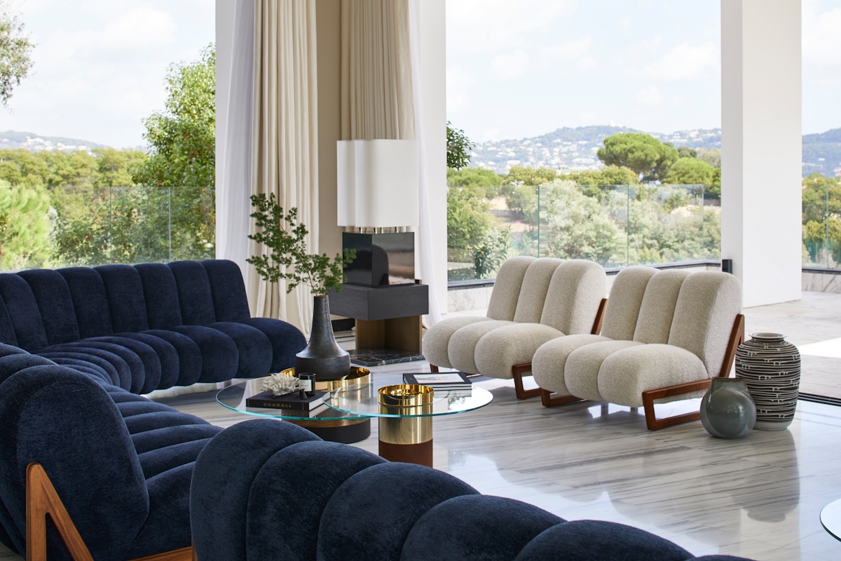 Humbert & Poyet Villa Odaya Mid-century Modern living room with glass coffee table and wraparound blue sofa