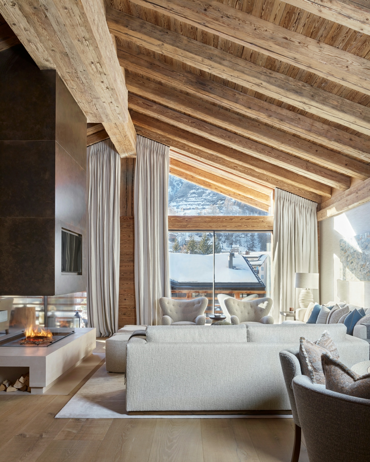 Katharine Pooley designed ski chalet interior with oak wood beams and floor, calming off-white upholstery and large open fireplace