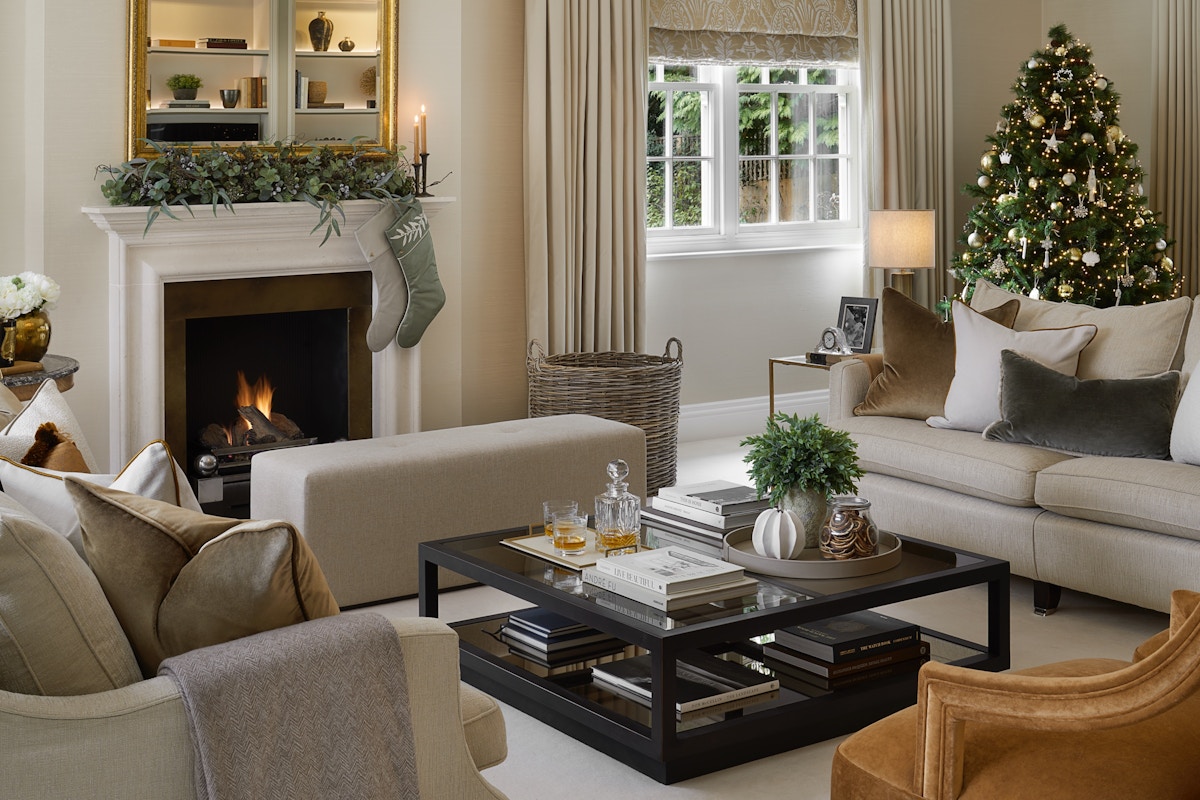 Living room in a luxury home at Christmas featuring a beautiful Christmas tree, stockings, designer furniture, decor and accessories.