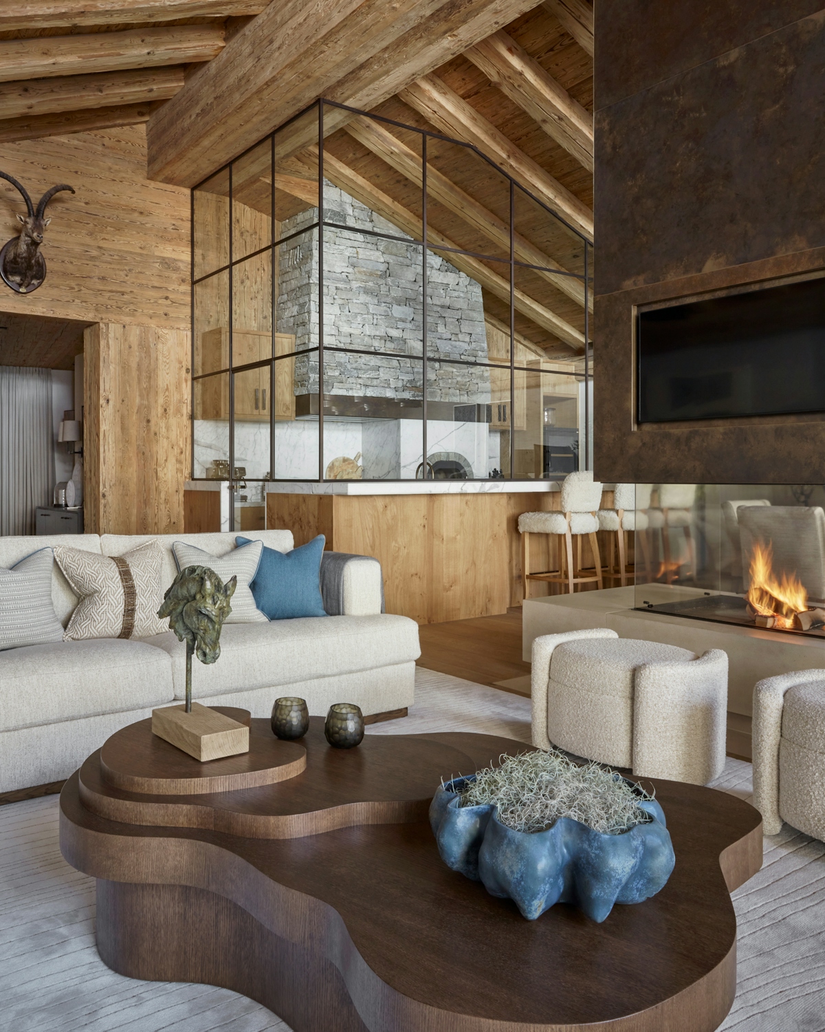 Katharine Pooley designed ski chalet with a large open fireplace, abstract wooden coffee table and large crittal windows