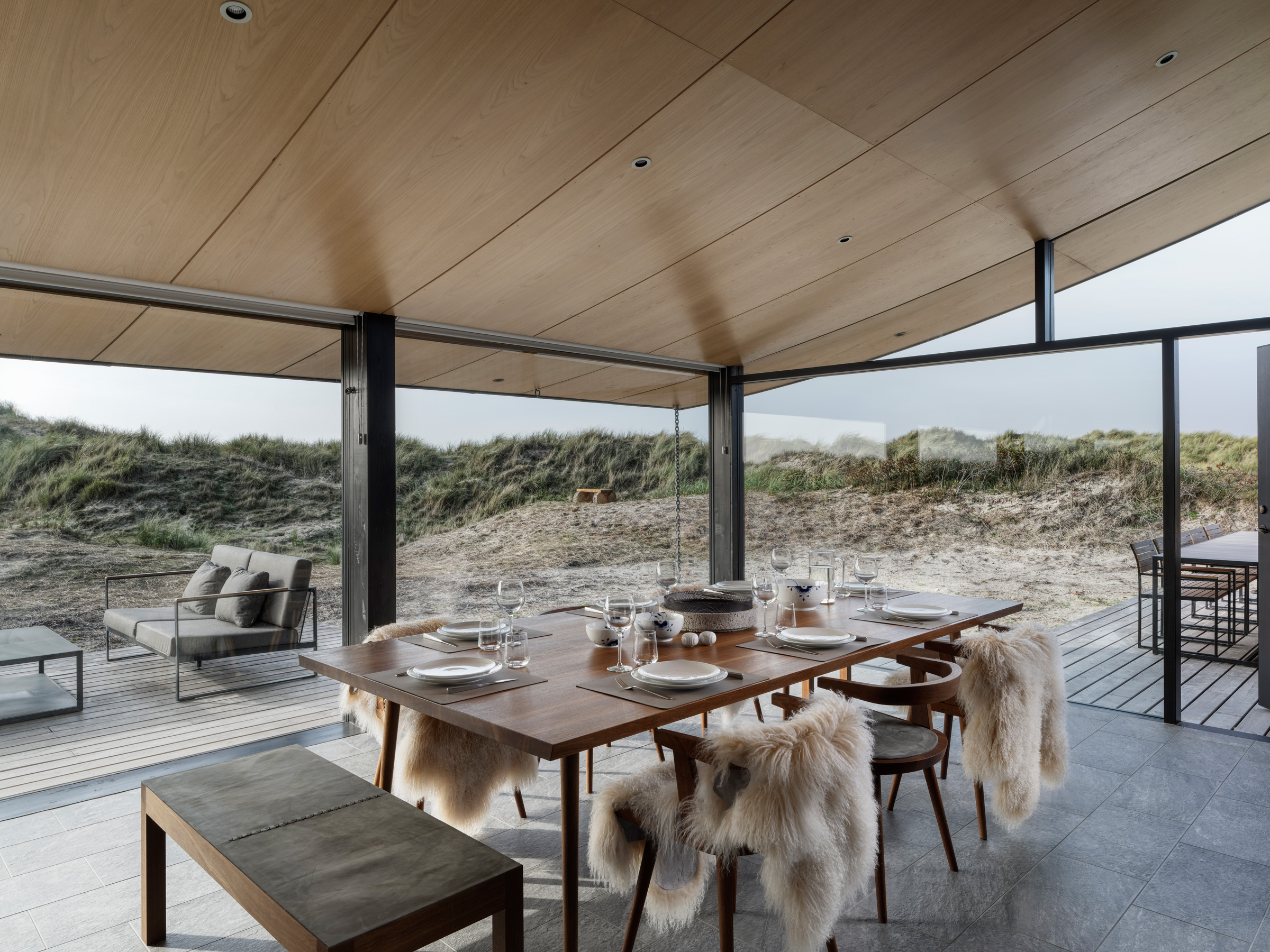Tollgard Studios scandi designed dining room with natural wood dining table and chairs with fur throws