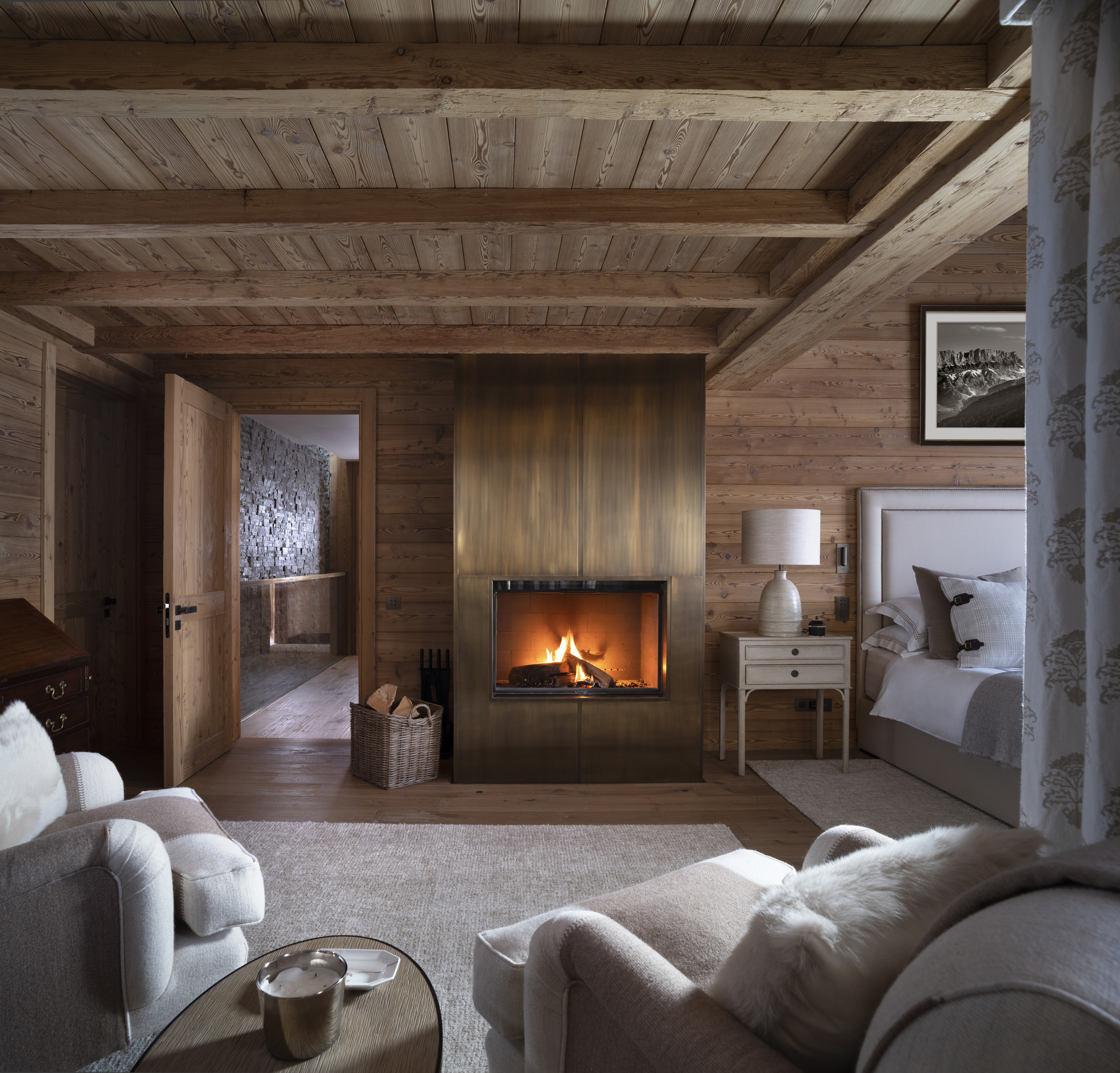 Nicky Dobree bedroom with open fireplace, textured cushions and rug with armchair and side table