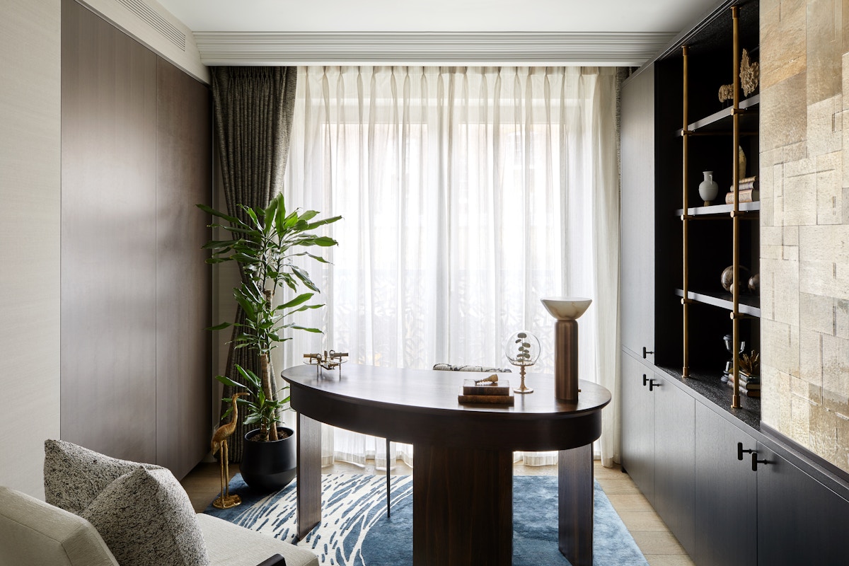 Home office with oval-shaped wooden desk, modern wood panelling on the left and a built-in shelving unit on the right