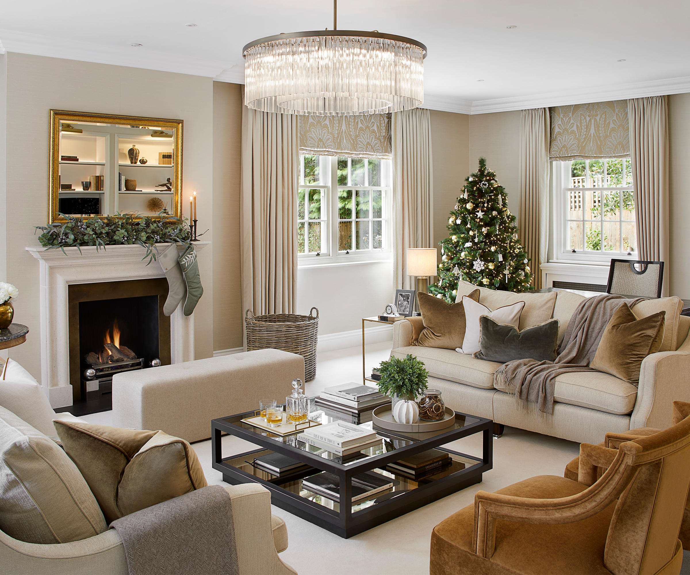 Luxury living room at Christmas featuring a tree with designer decorations, an open fireplace, beautiful furniture, home decor and accessories
