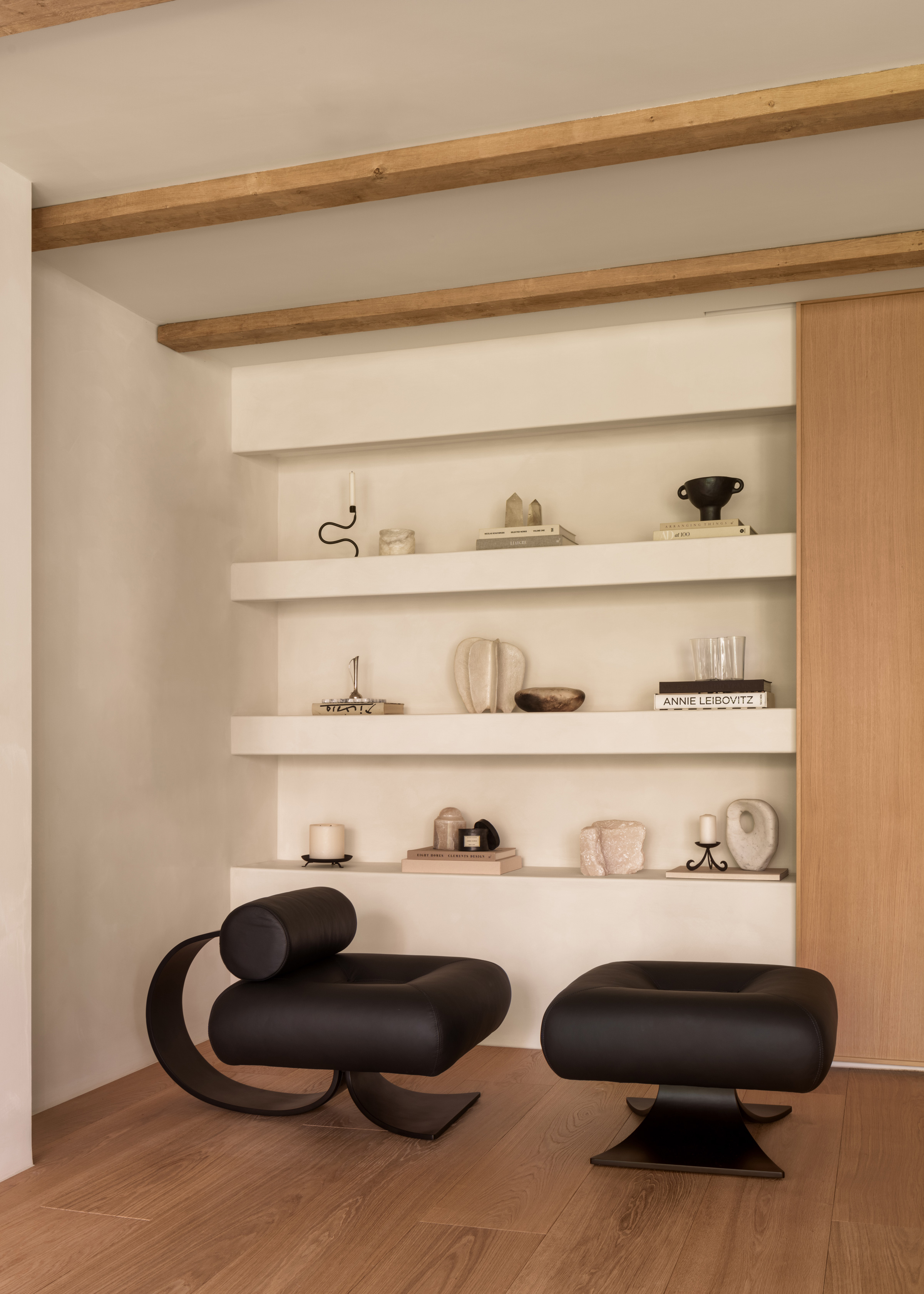 Covet Noir shelving with abstract ornaments and two minimalist black stools