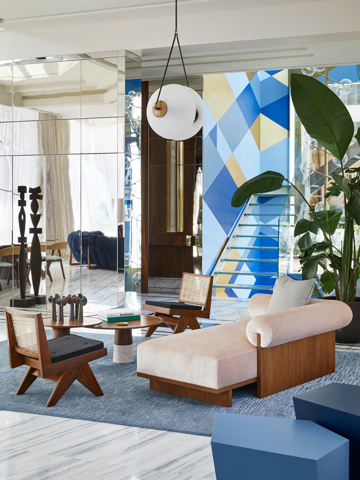 Humbert & Poyet Villa Odaya Mid-century Modern living area with blue rug, chaise lounge, geometric design on stairwell