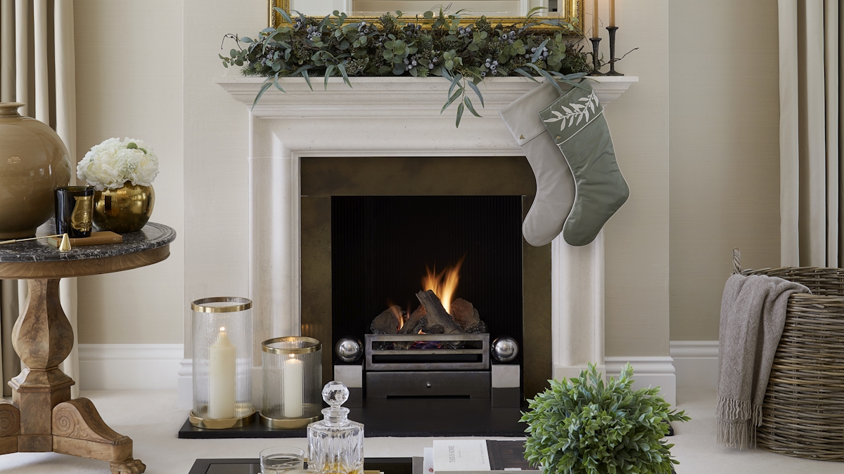 A Christmas fireplace decorated with two hanging stockings and foliage on the mantel. 