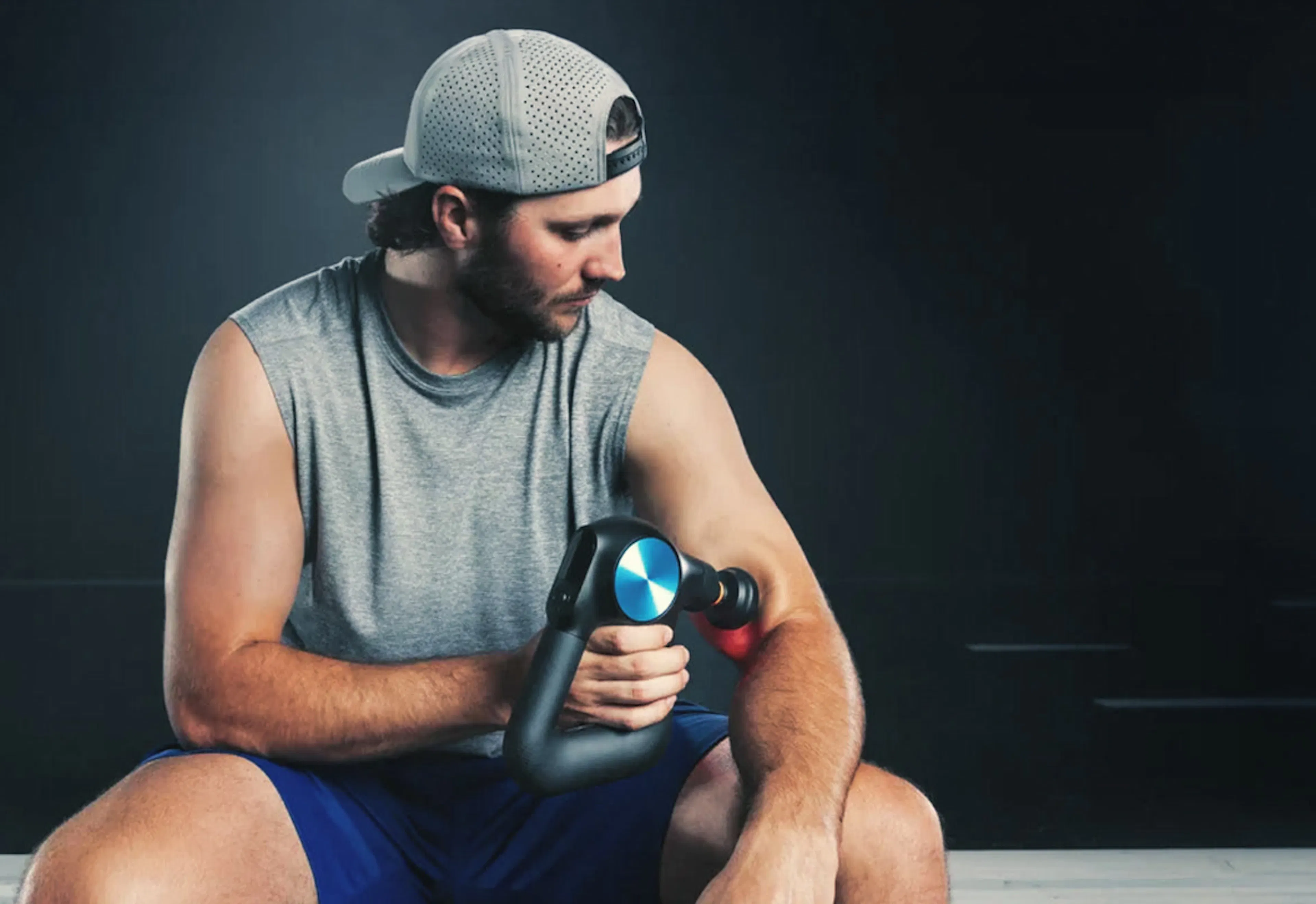 Athlete using a Theragun percussive massage device after training