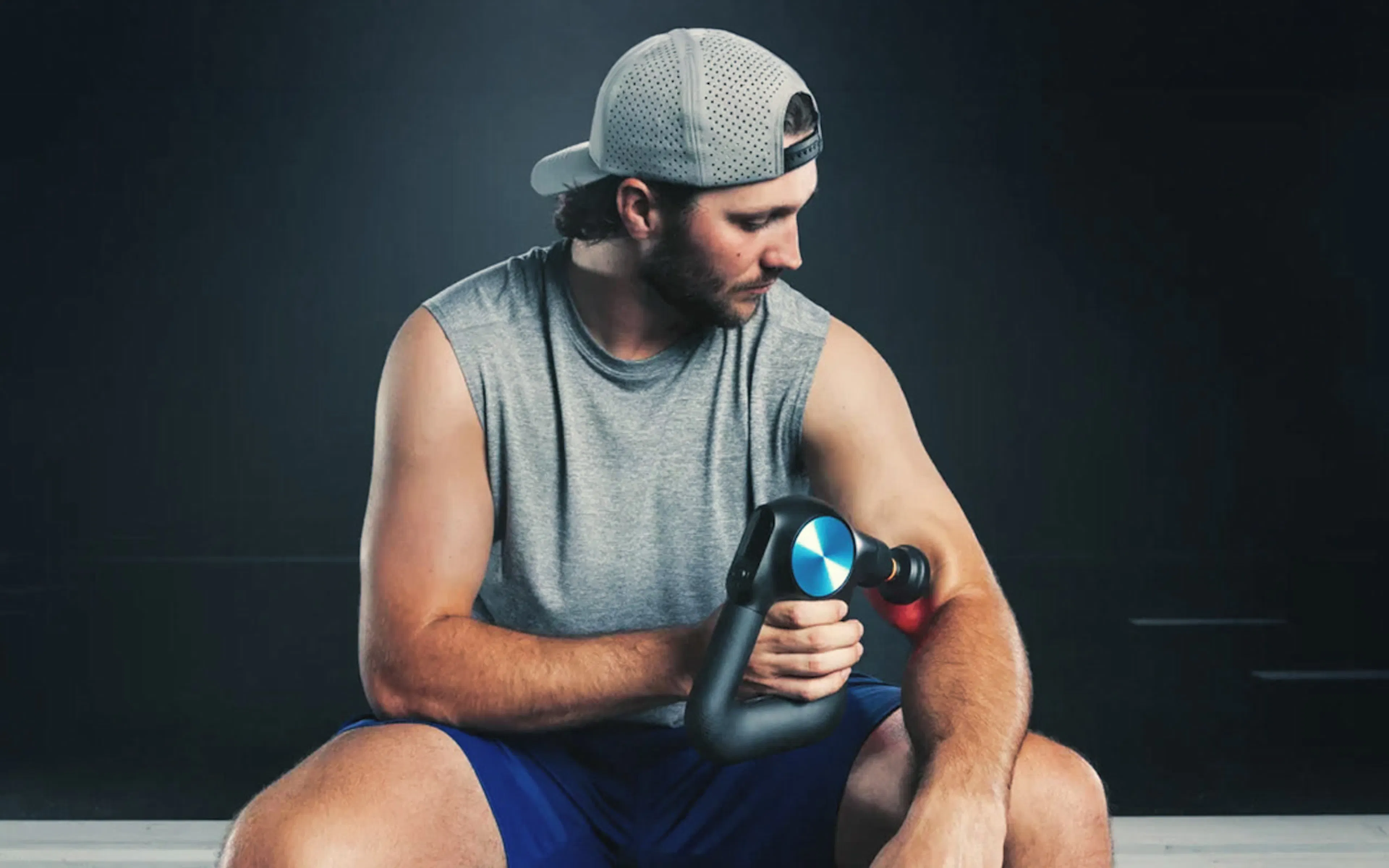 Athlete using a Theragun percussive massage device after training